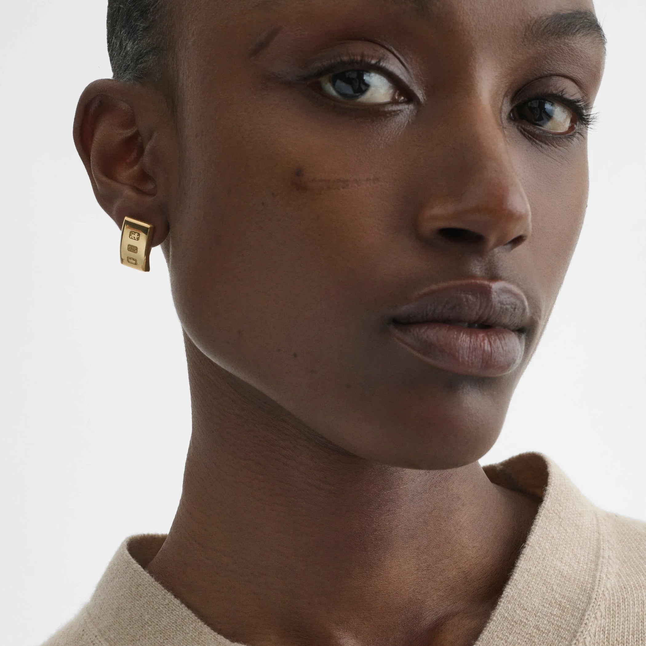 Front view of model wearing hallmark earrings in gold plated sterling silver.