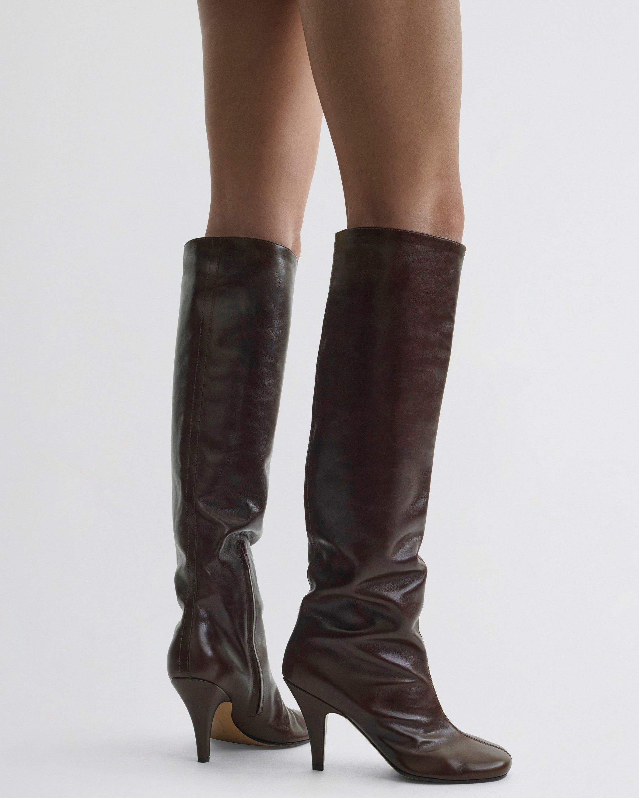 Side view of model wearing Knee-High Boot in oxblood leather