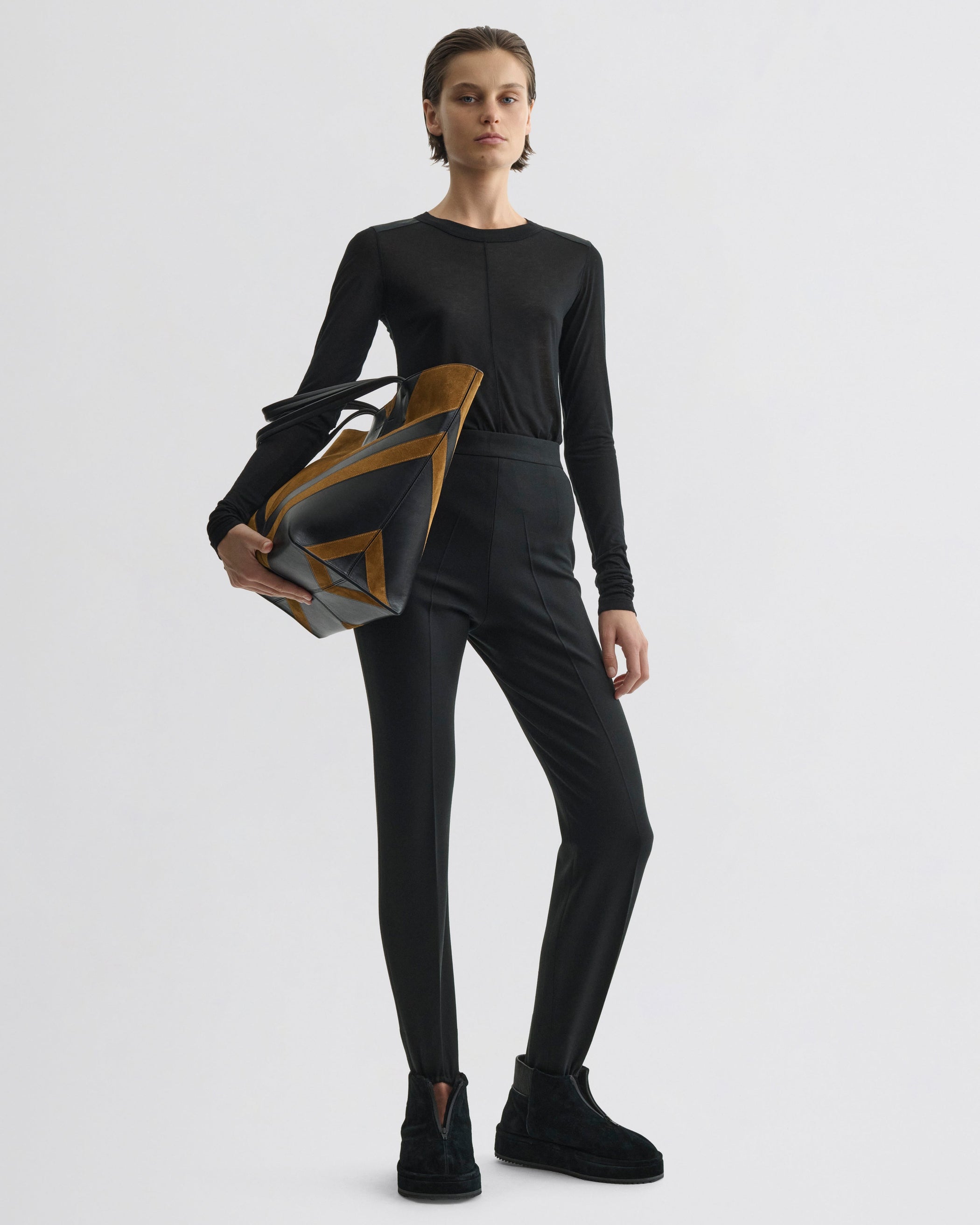 Front view of model wearing Stirrup Trousers in black wool