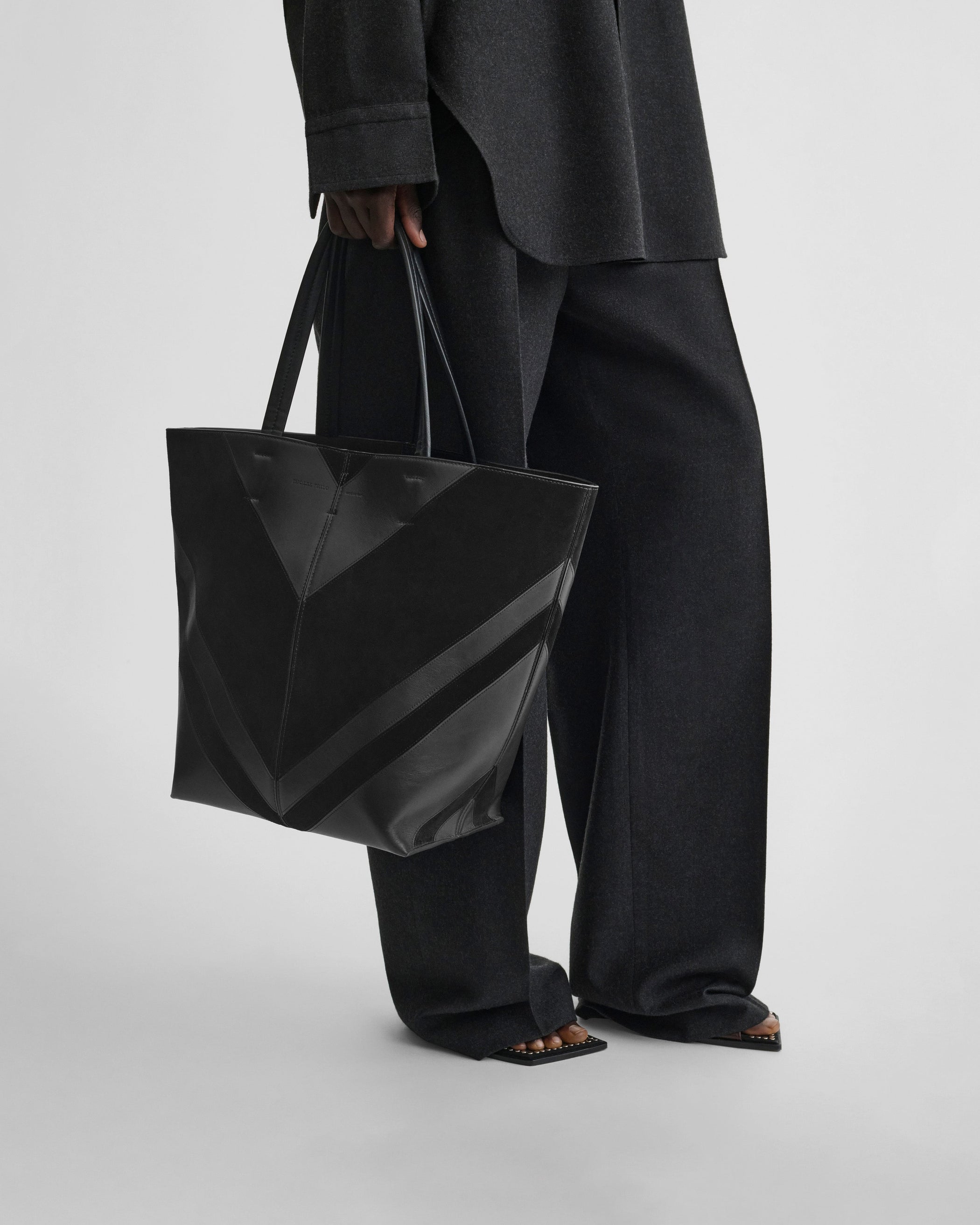 Model holding POT CABAS BAG in black suede leather