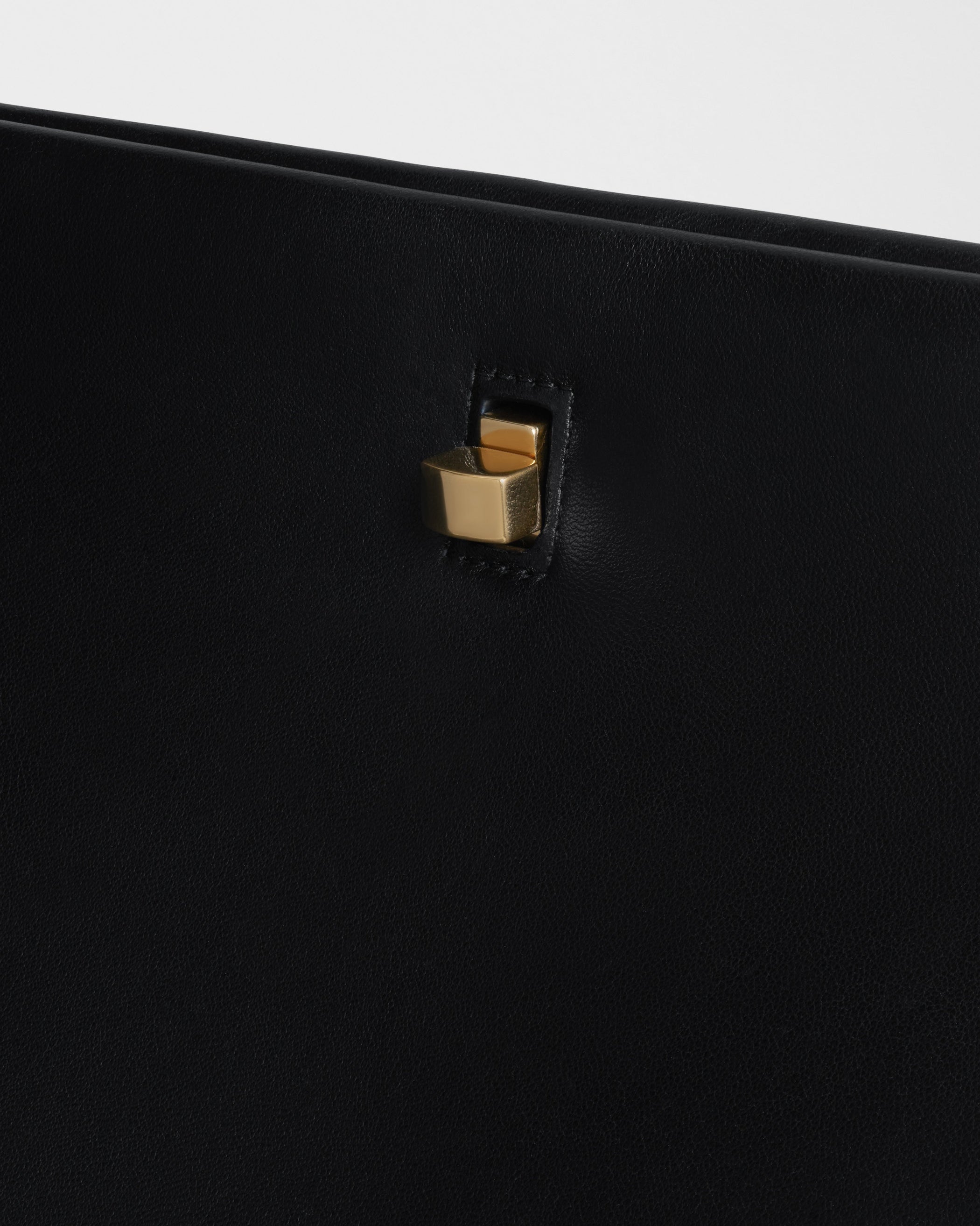 Close up view of the fastening of the TRIPLEX CLUTCH BAG in black leather