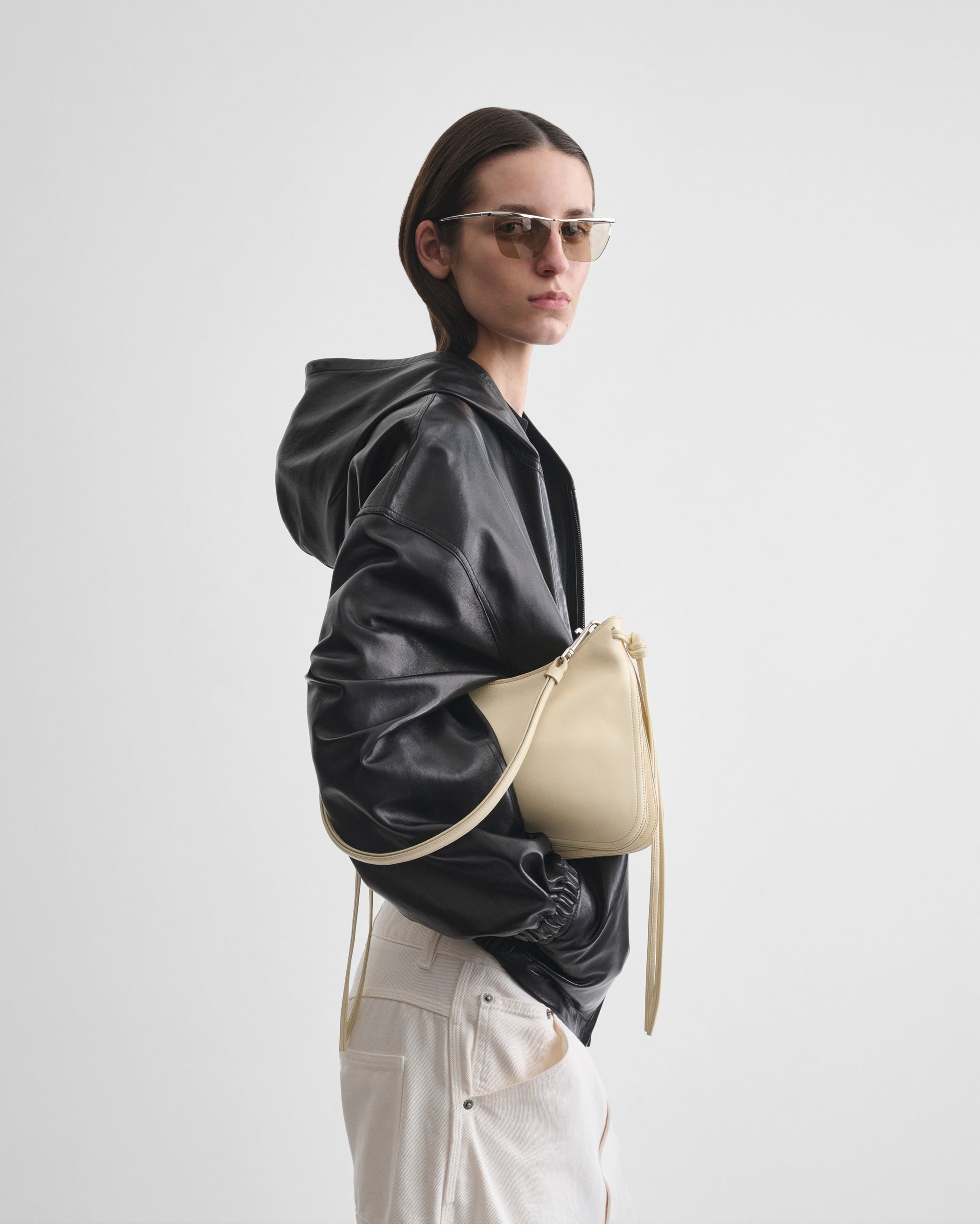 Side view of model holding SMALL GIG BAG in stucco leather