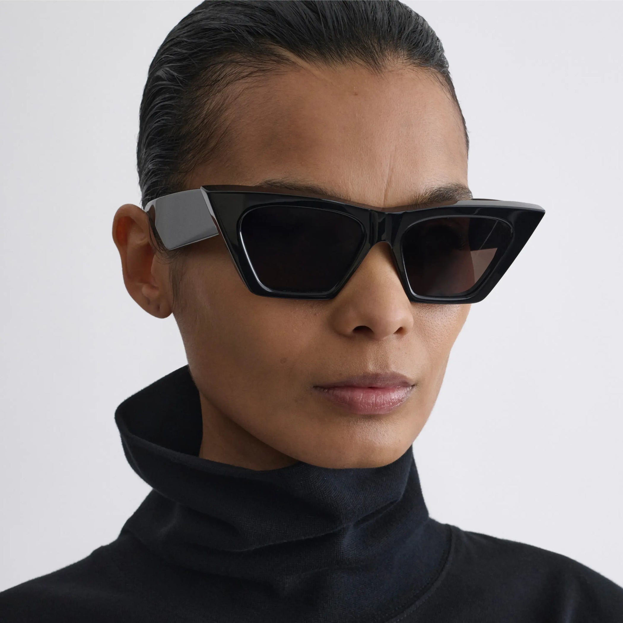 Side view of model wearing peak sunglasses in black acetate.