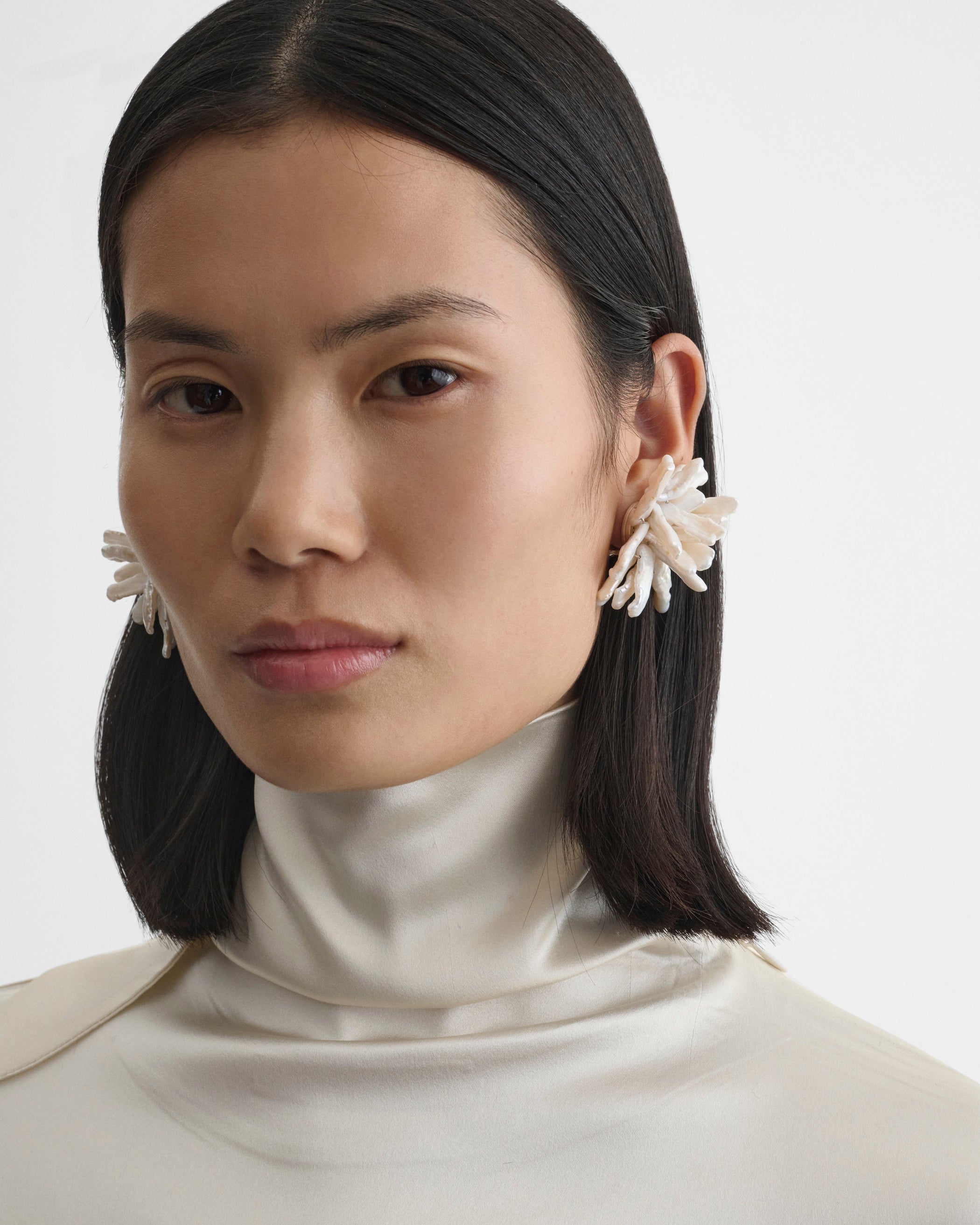 Front view of model wearing HCLUSTER EARRINGS in silver cream resin