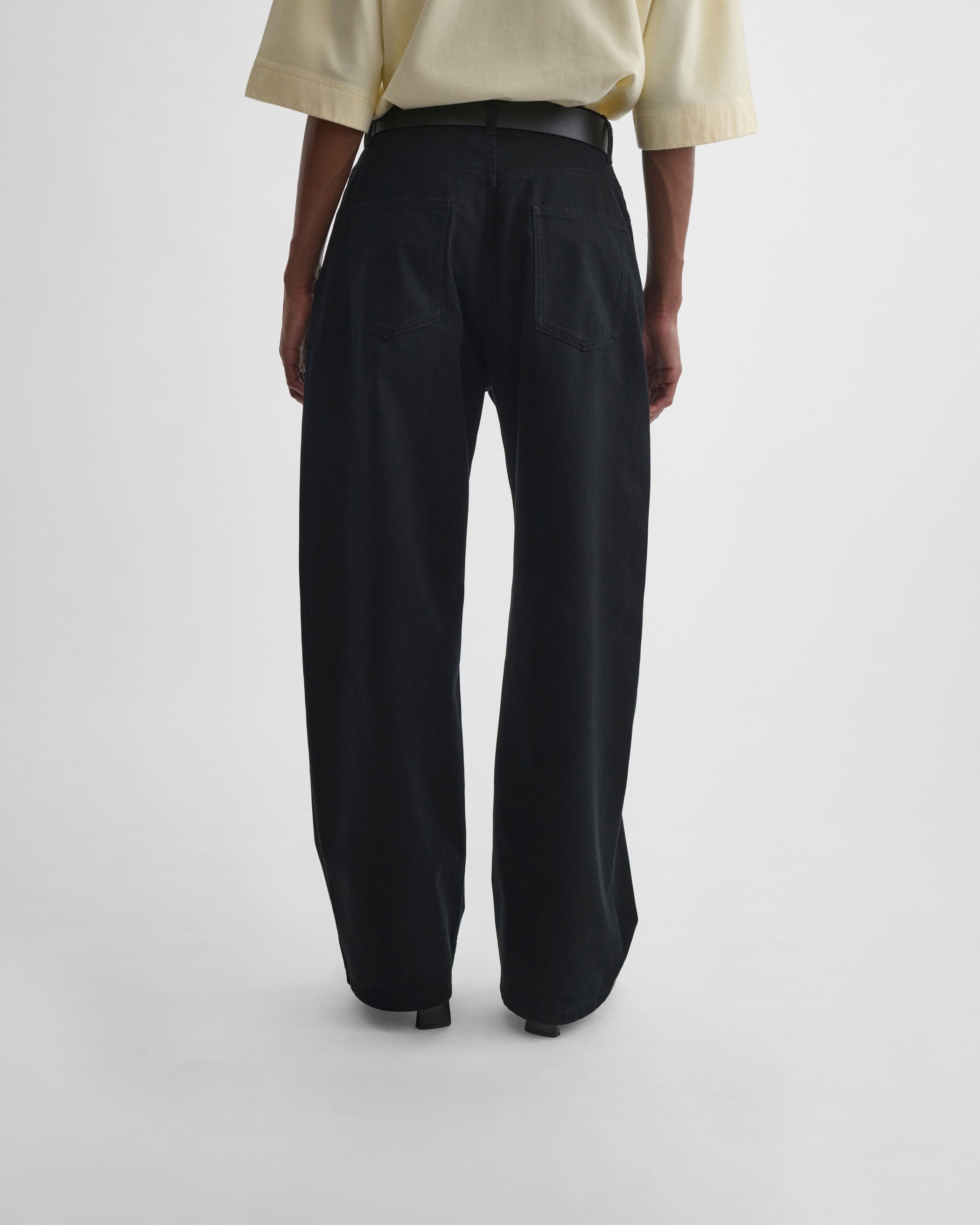 Back view of model wearing DROP JEANS in black cotton