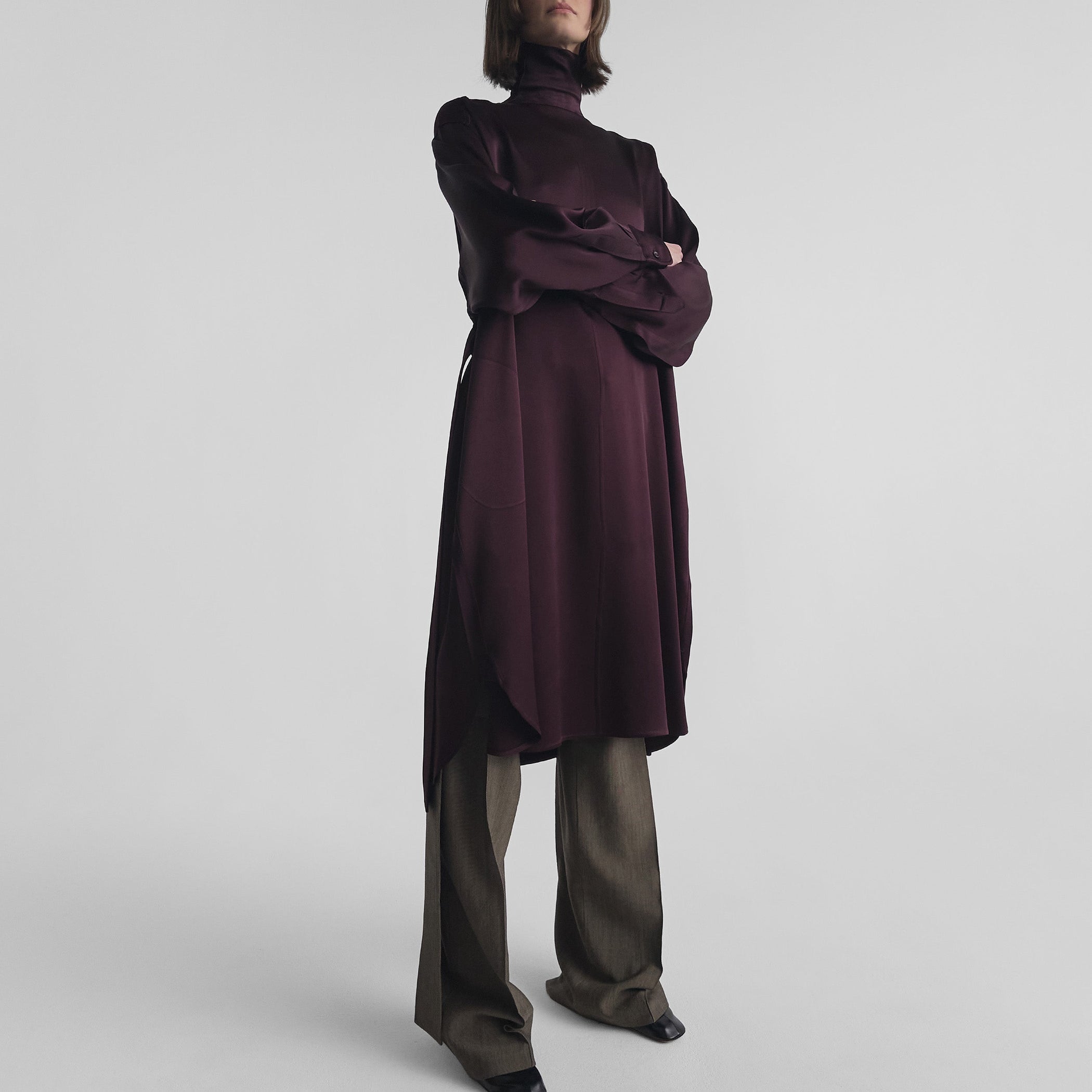 Front view of model with crossed arms wearing DRESS in dark berry satin back crepe