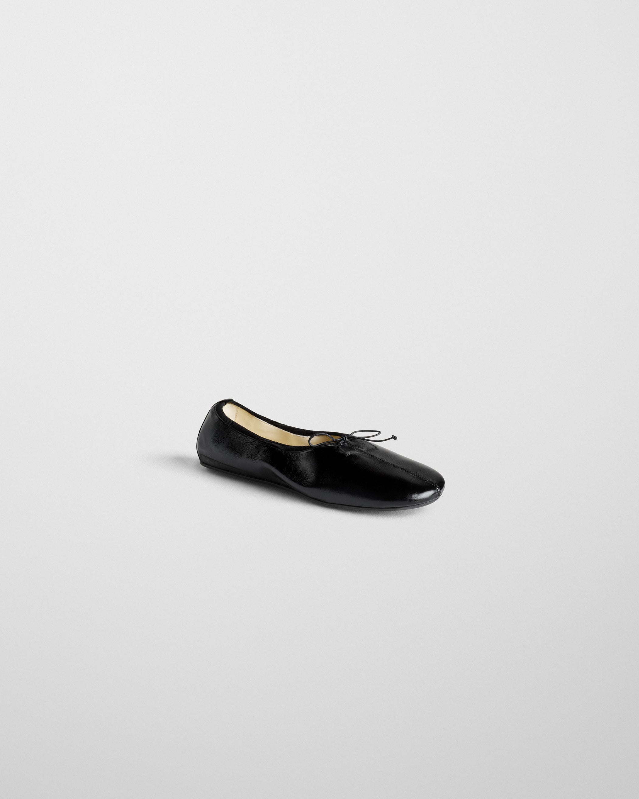 Angled side view of GATHERED FLAT in black leather