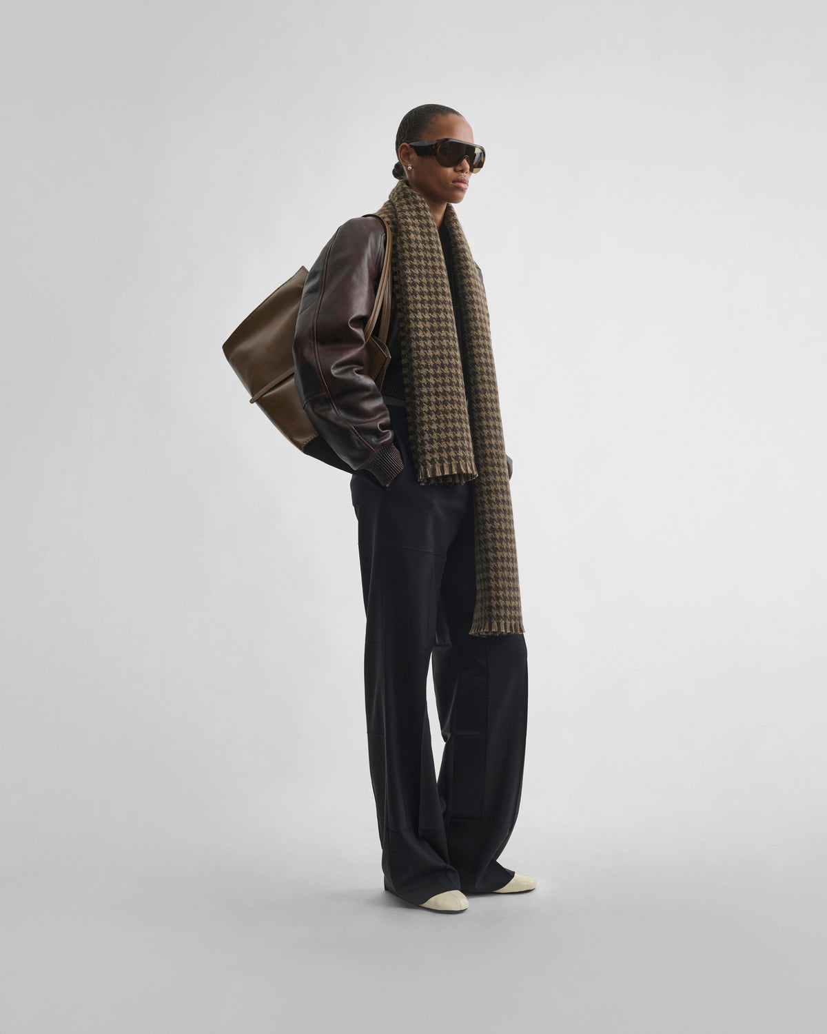 Angled front view of model wearing SHRUNK BOMBER in conker leather