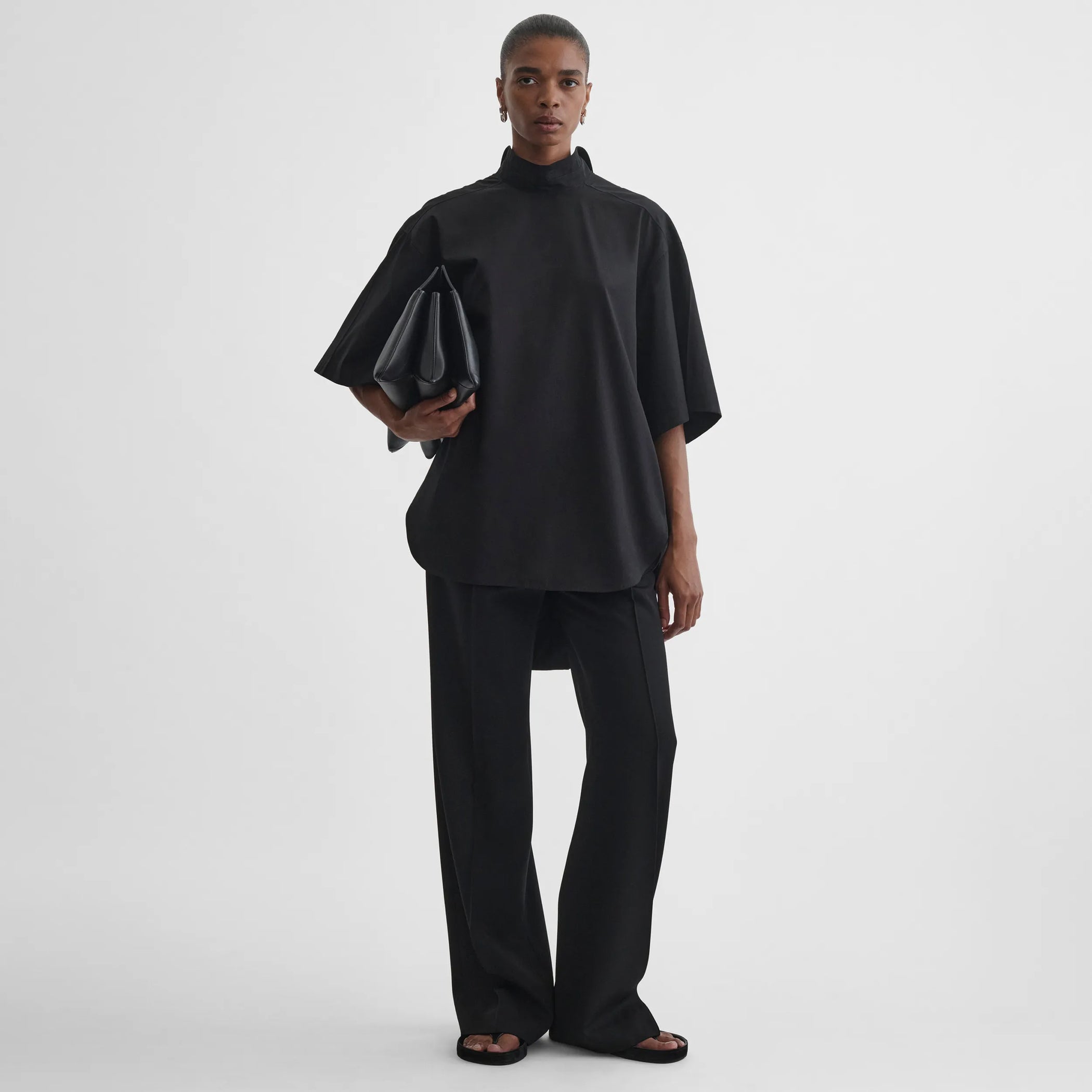 Front full body view of model wearing tie neck short sleeve shirt in black cotton