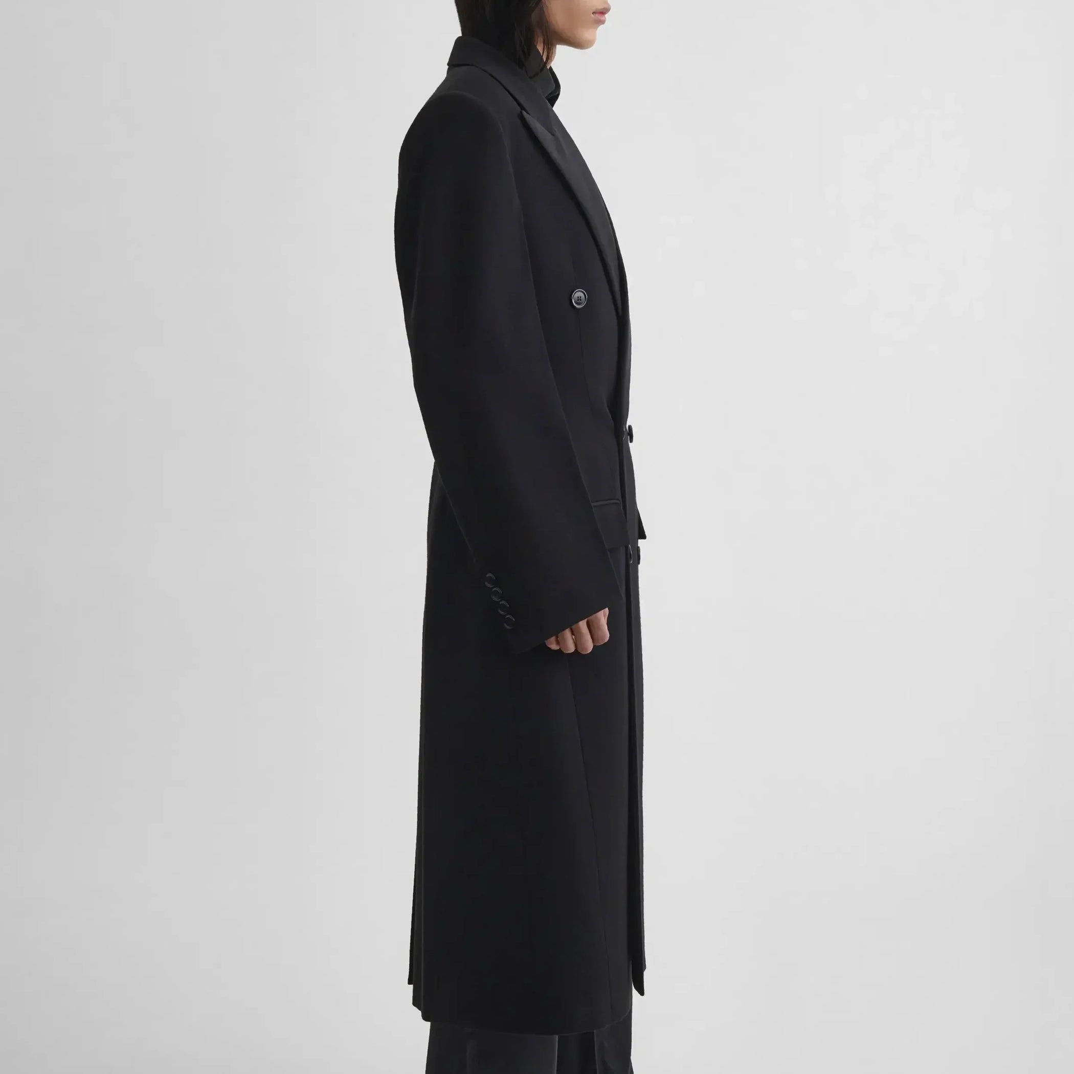 Side view of model wearing TAILORED COAT WITH DROPPED WAIST in black wool