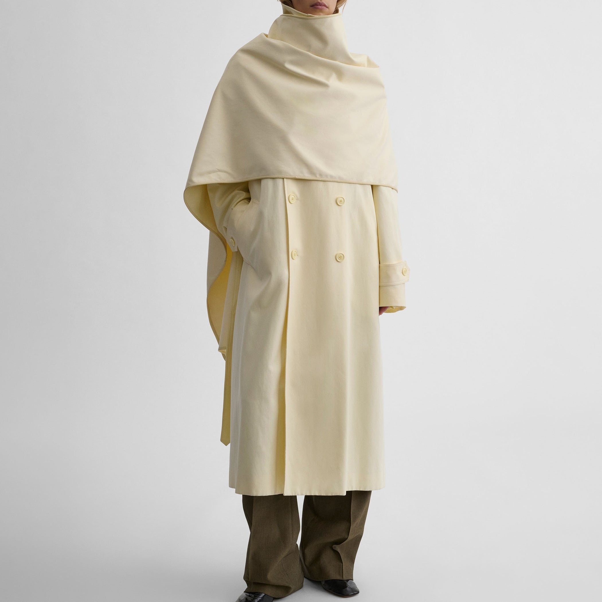 Front view of model wearing TRENCH COAT WITH ATTACHABLE SCARF in cream technical polyester