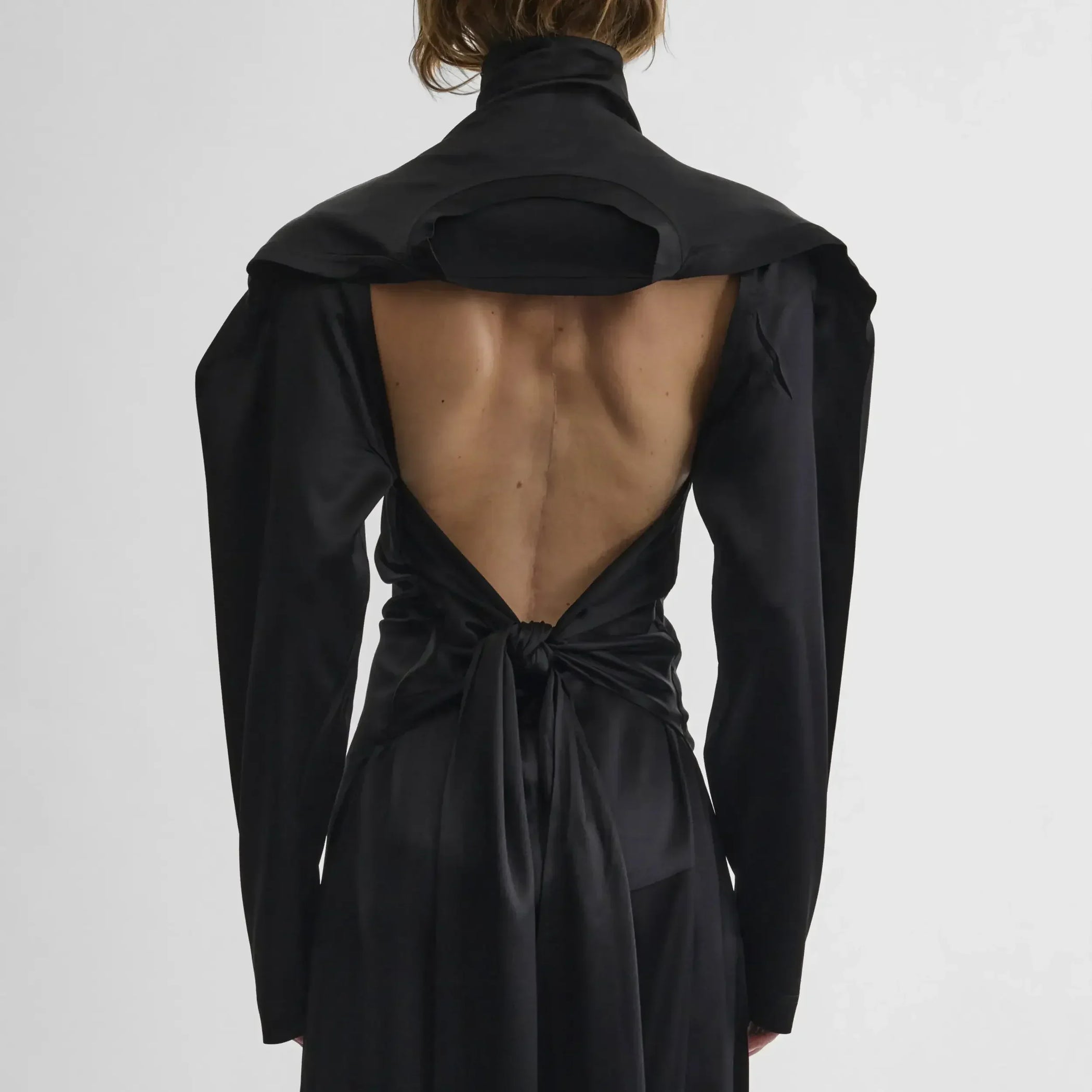 Back view of model wearing LIQUID OPEN BACK DRESS in black silk satin