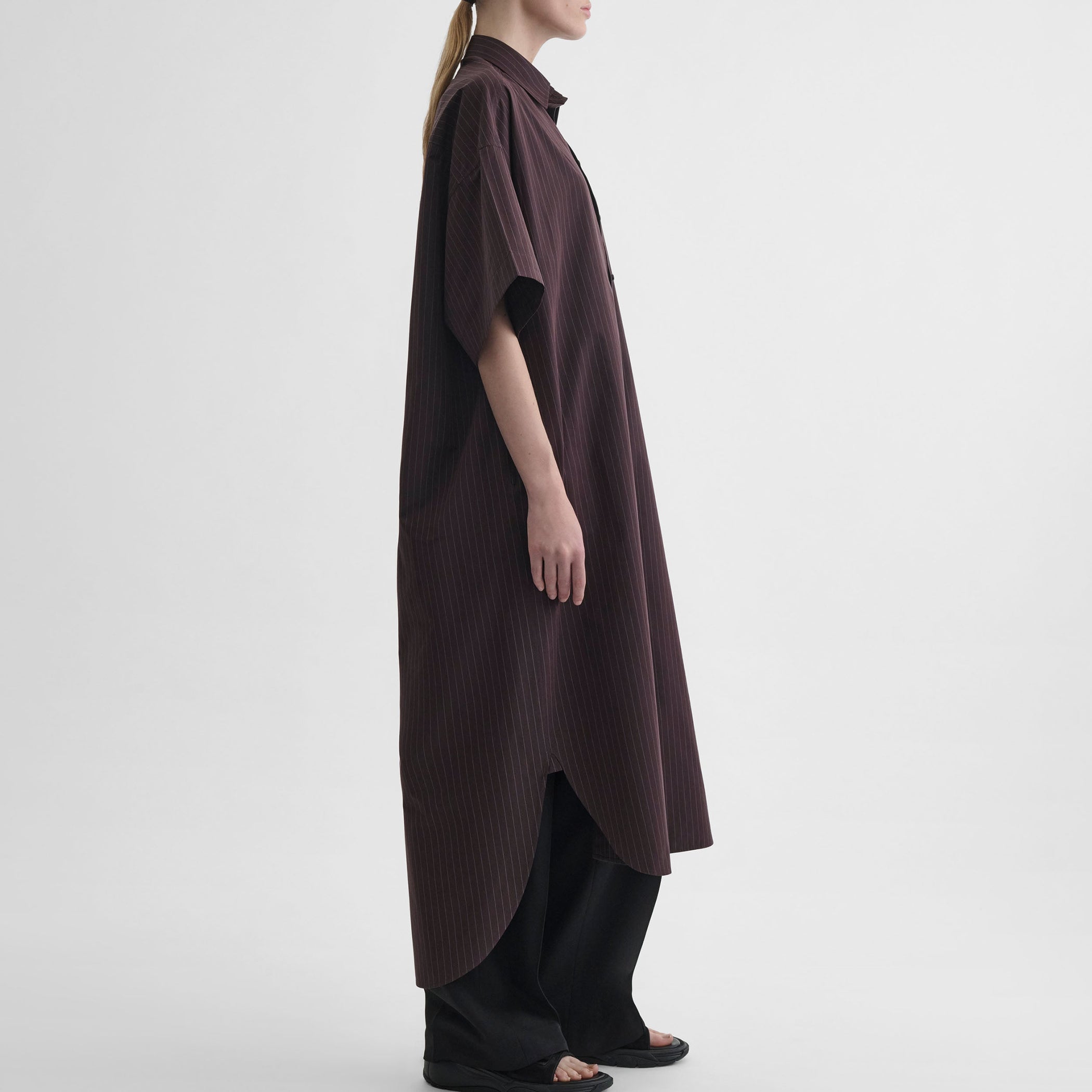 Side view of model wearing LONG SHIRT DRESS in black cherry cotton