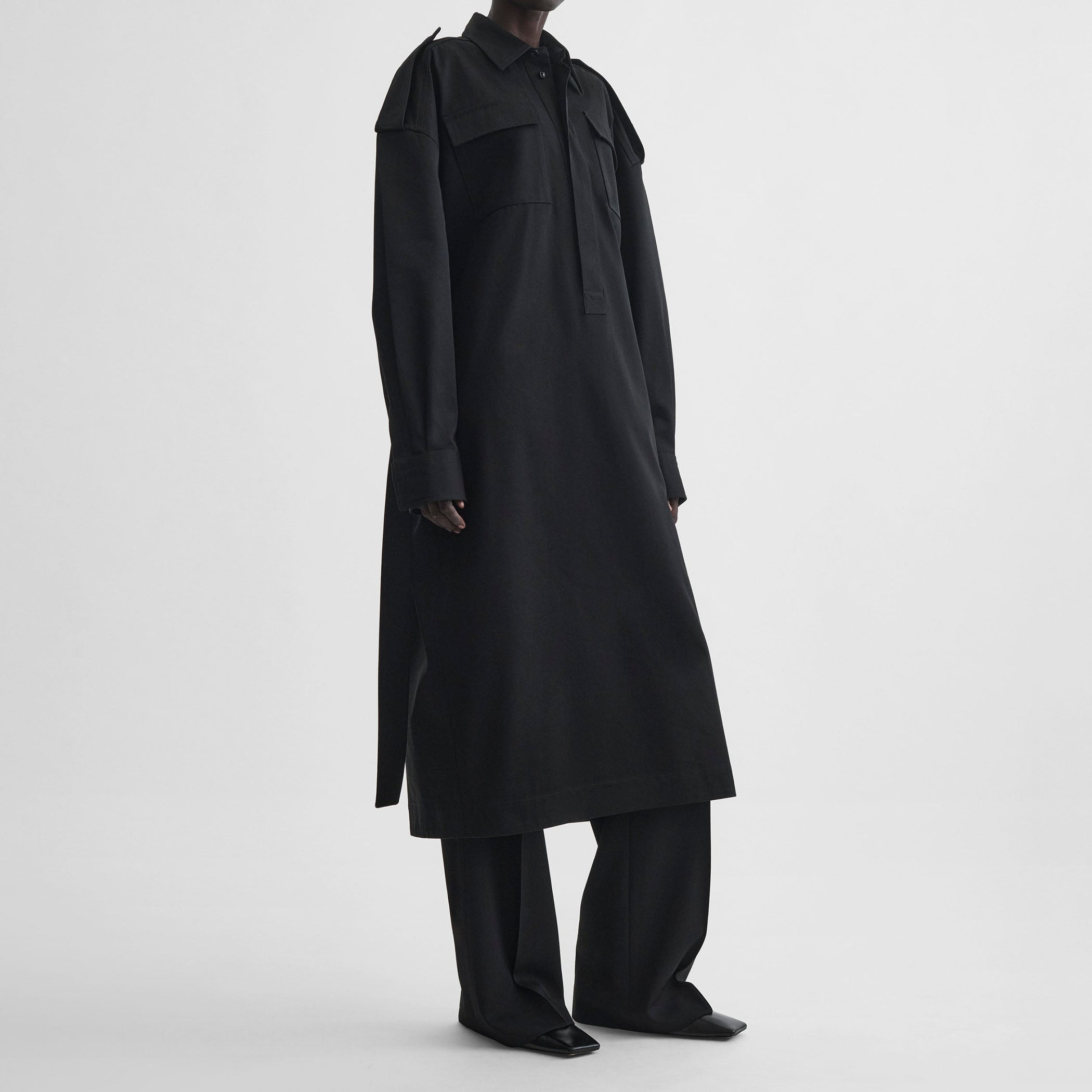 Side view of model wearing UTILITY SHIRT DRESS in black cotton