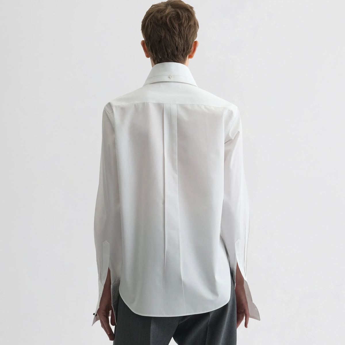 Back view of model wearing tuxedo shirt in white cotton.