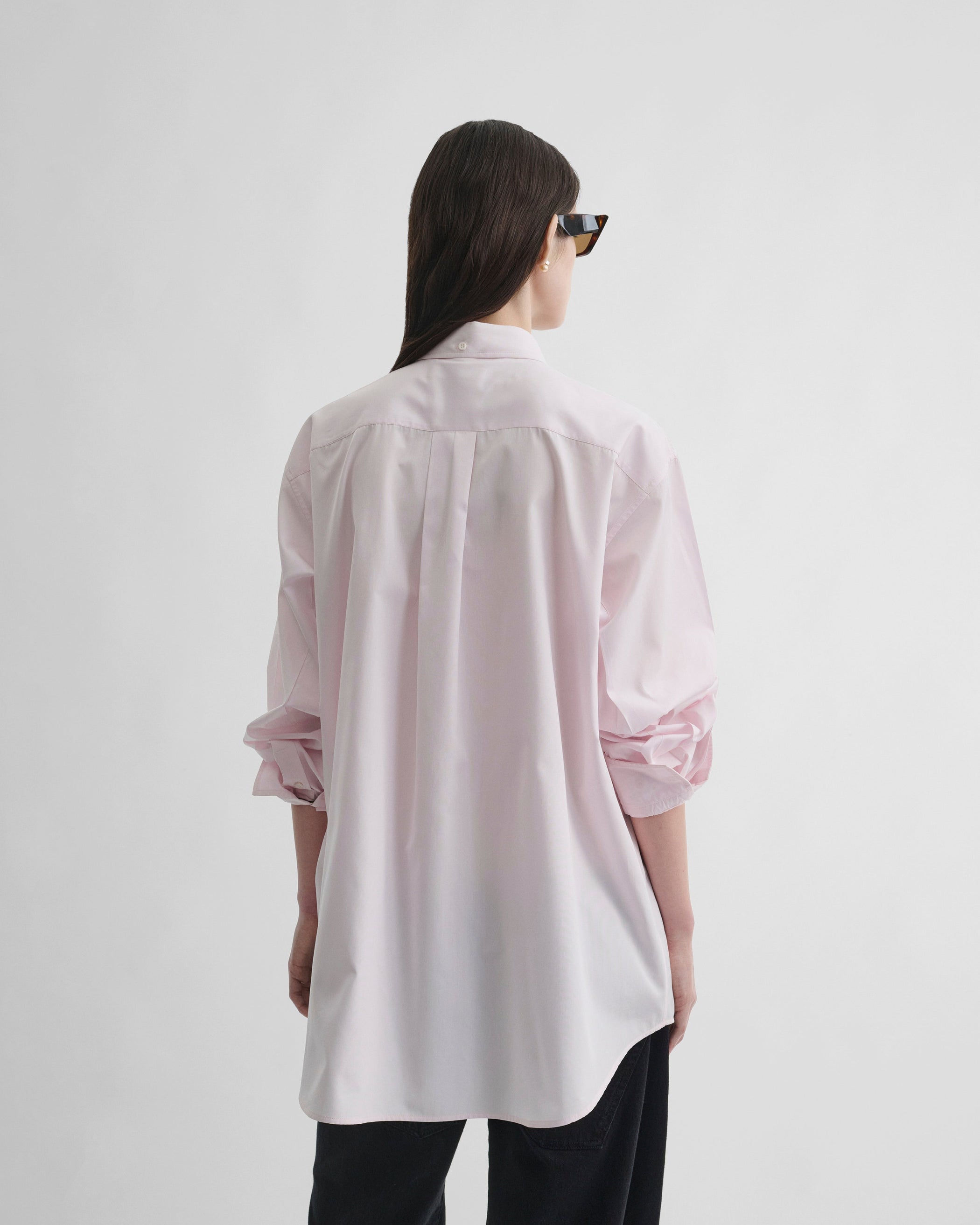 Back view of model wearing BUTTON COLLAR SHIRT in pale pink cotton