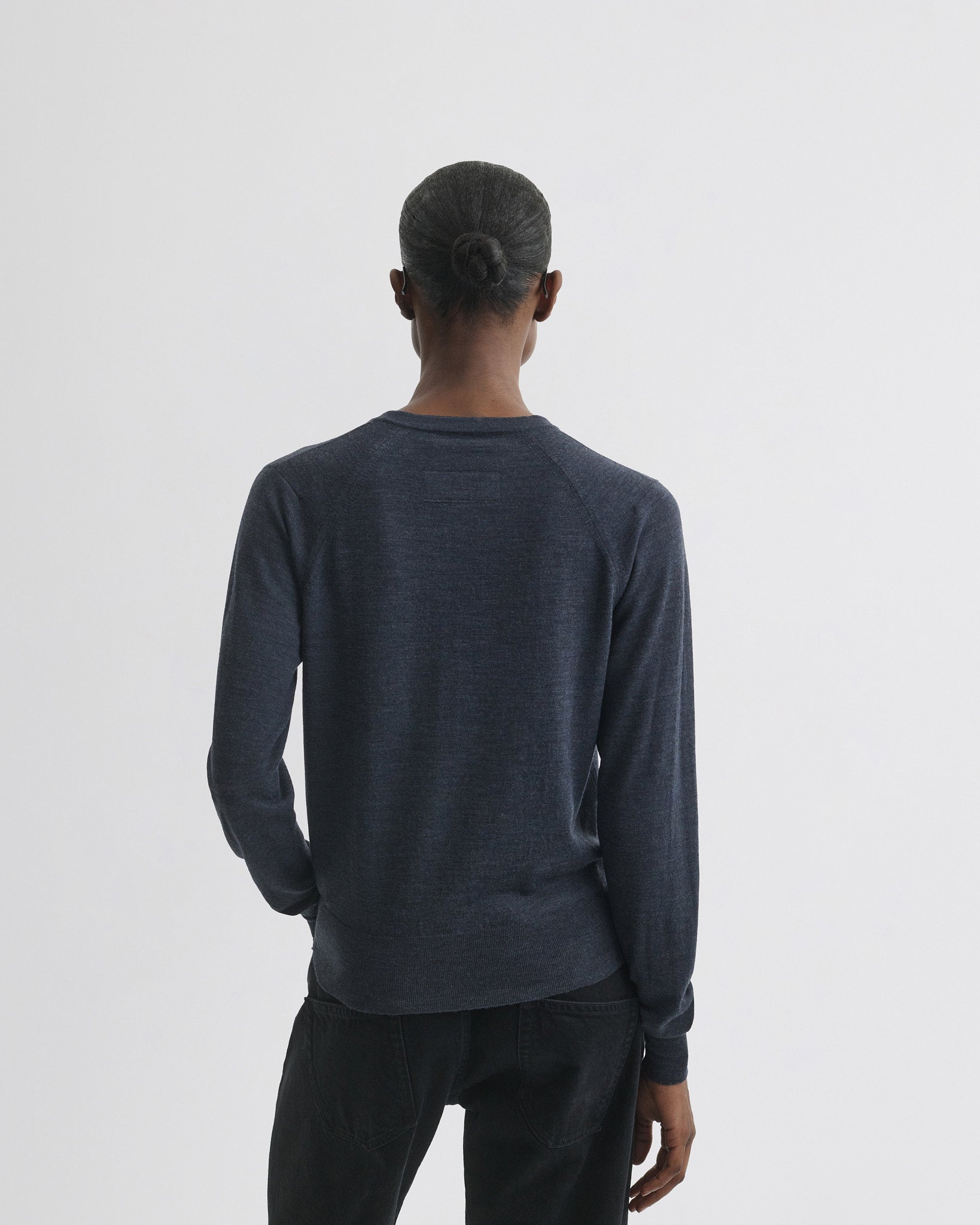 Back view of model wearing shrunk v-neck in dark blue melange wool.