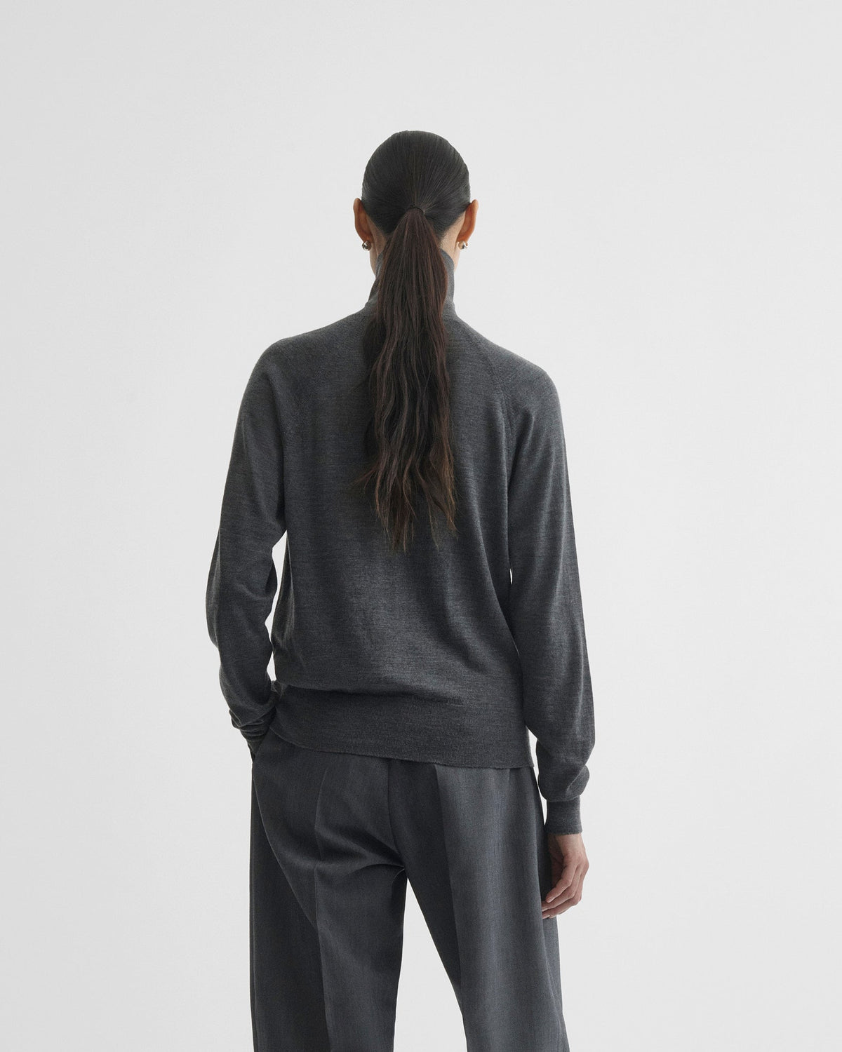 Back view of model wearing HIGH NECK JUMPER in anthracite melange wool