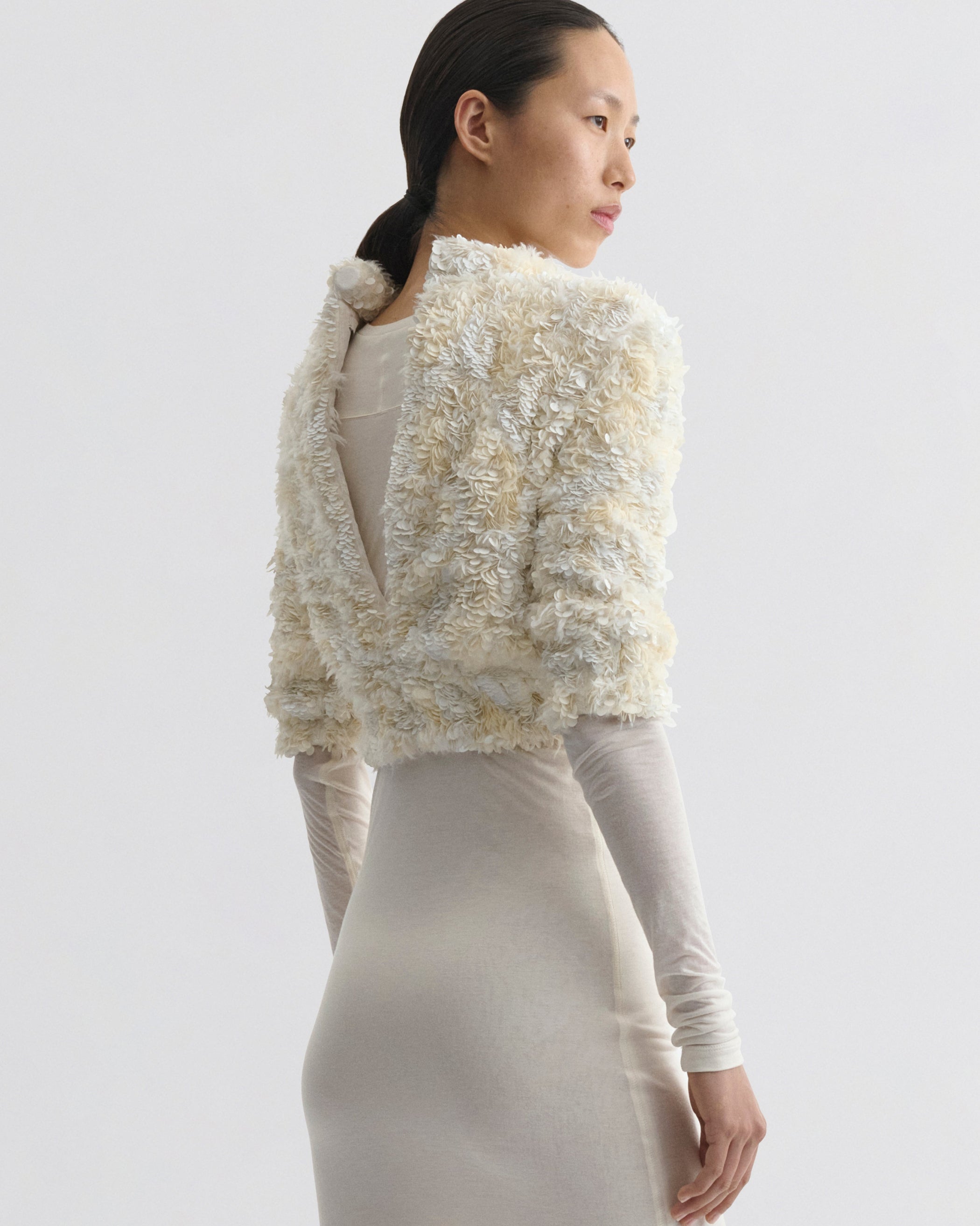 Back view of model wearing CLUSTERED SEQUIN DRESS in ivory jersey