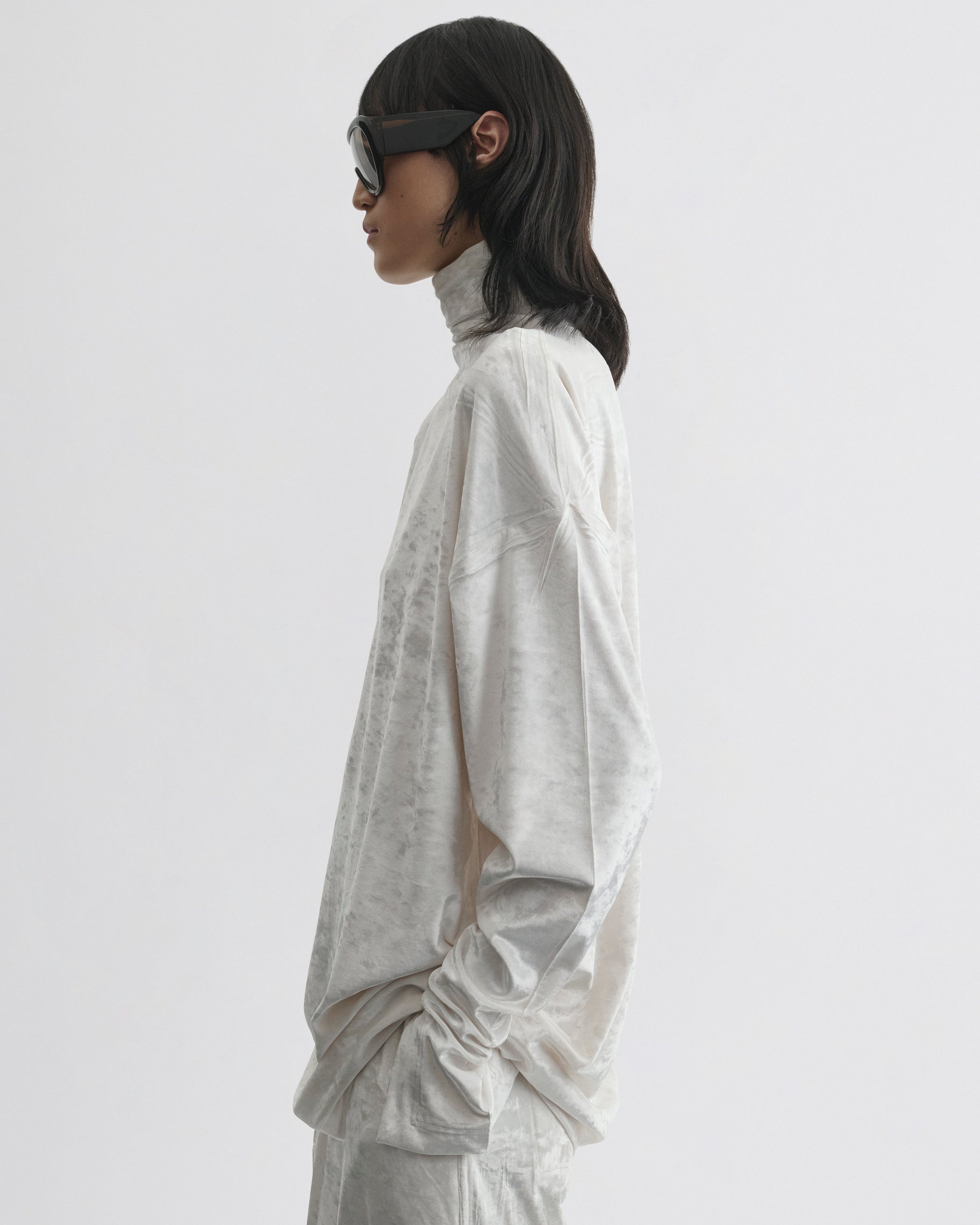 Side view of model wearing LIQUID HIGH NECK TOP in white crushed velvet