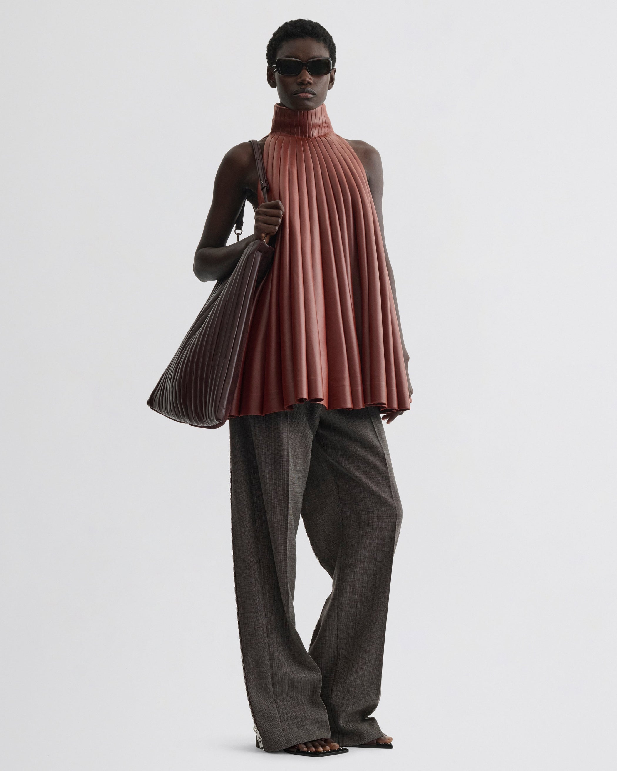 Front view of model wearing Accordion Top in brick bonded jersey