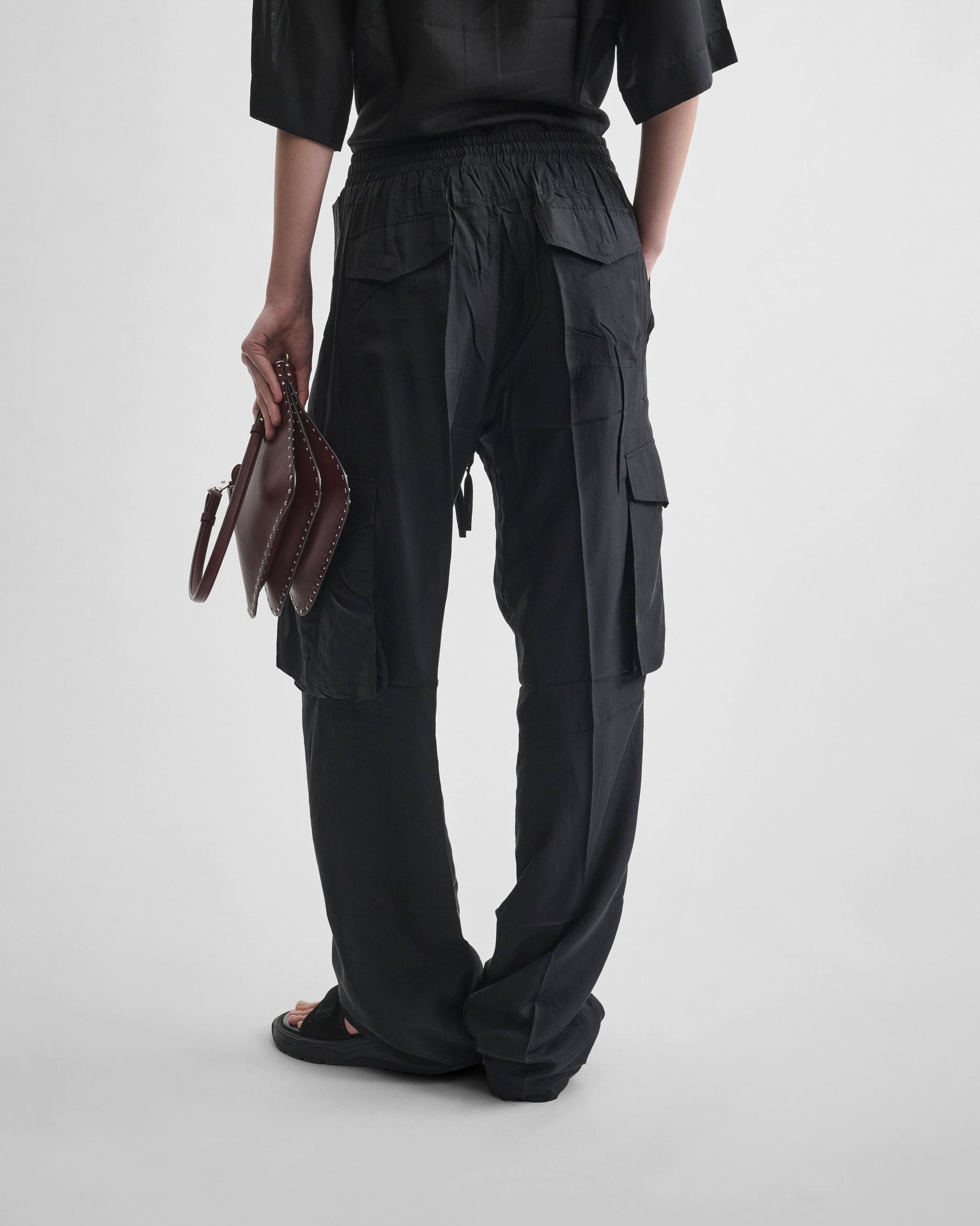 Back view of model wearing CARGO TROUSERS in black silk