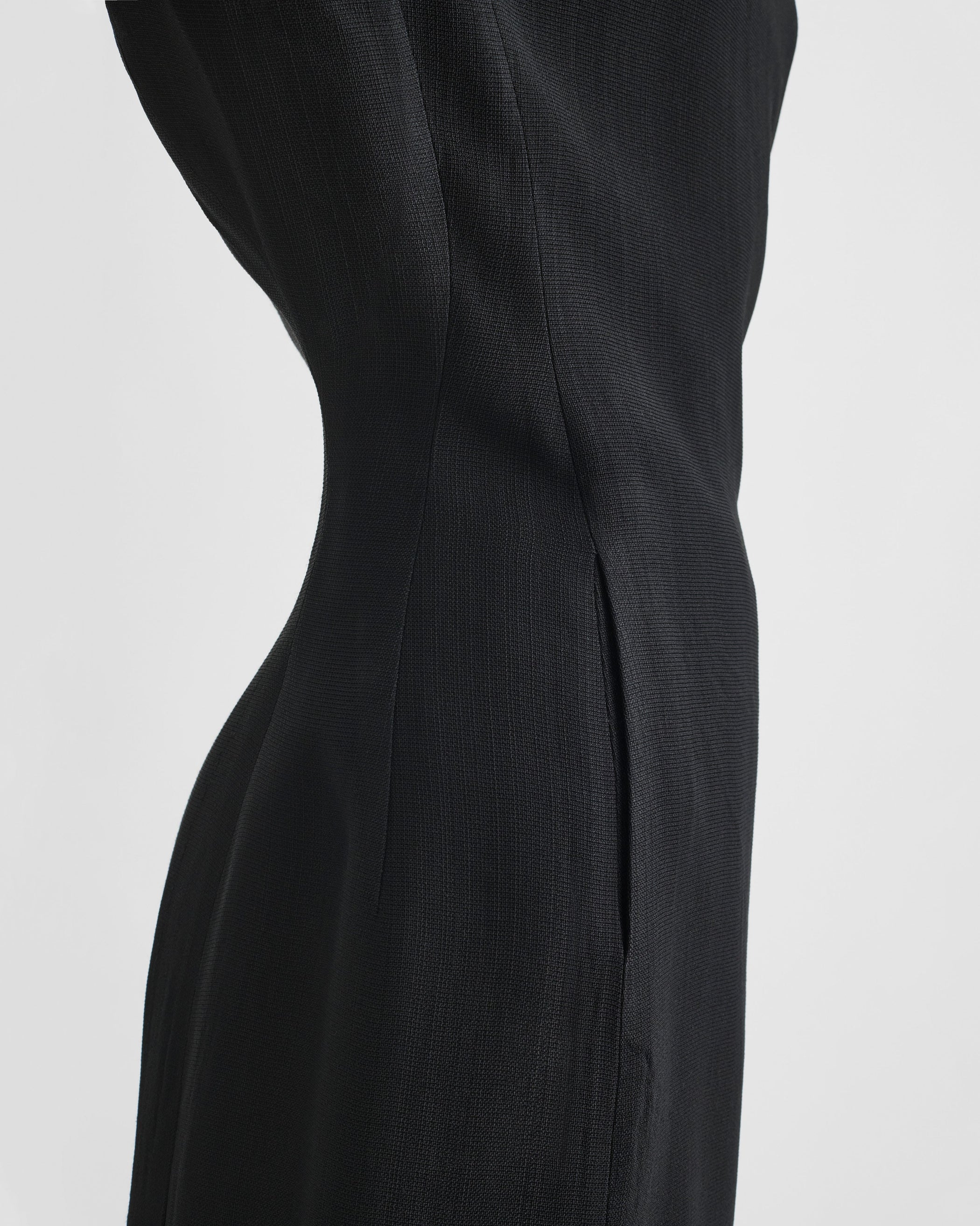 Detail side view of model wearing KINKED TAILORED DRESS in black viscose
