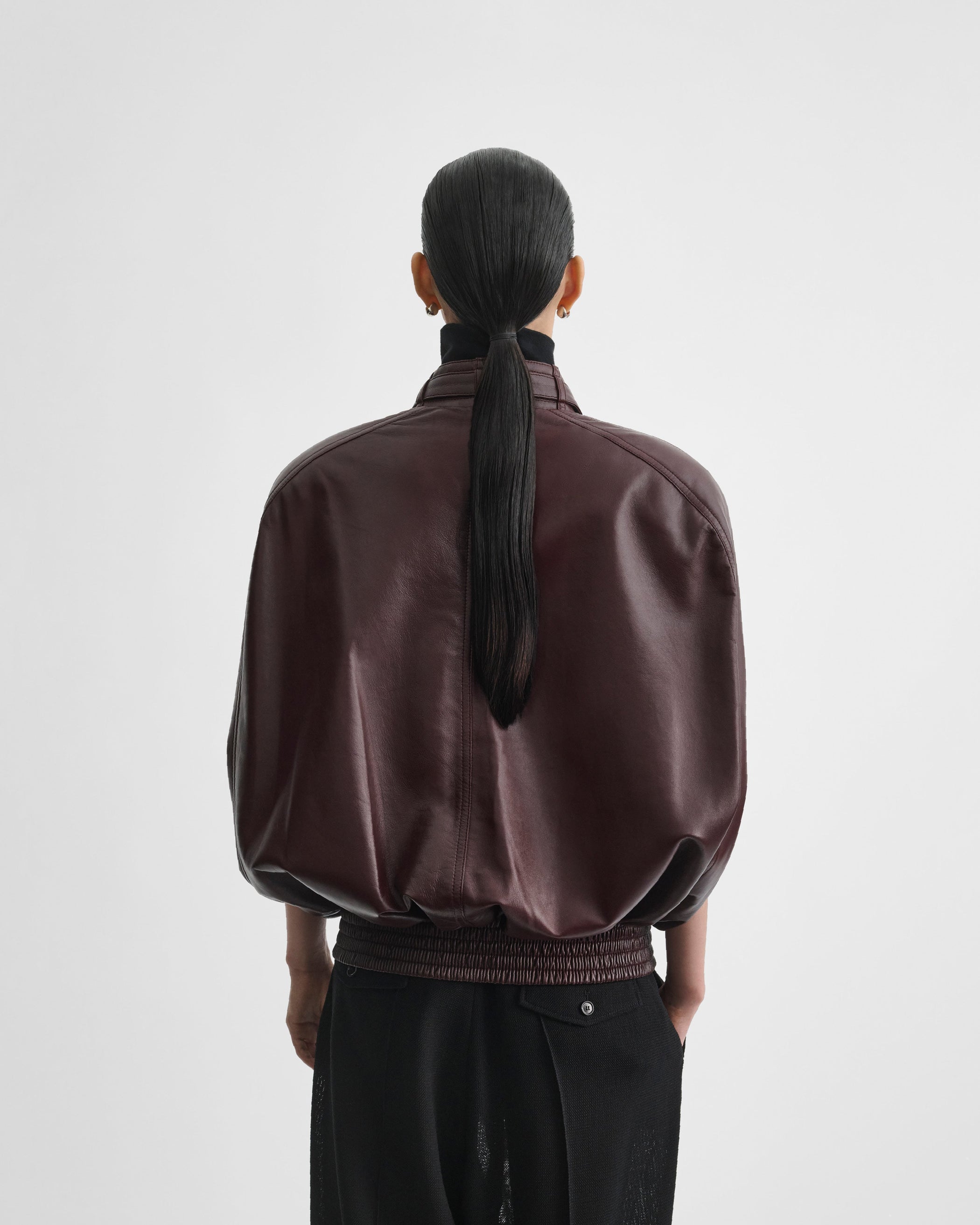Back view of model wearing CAPE BOMBER in merlot leather
