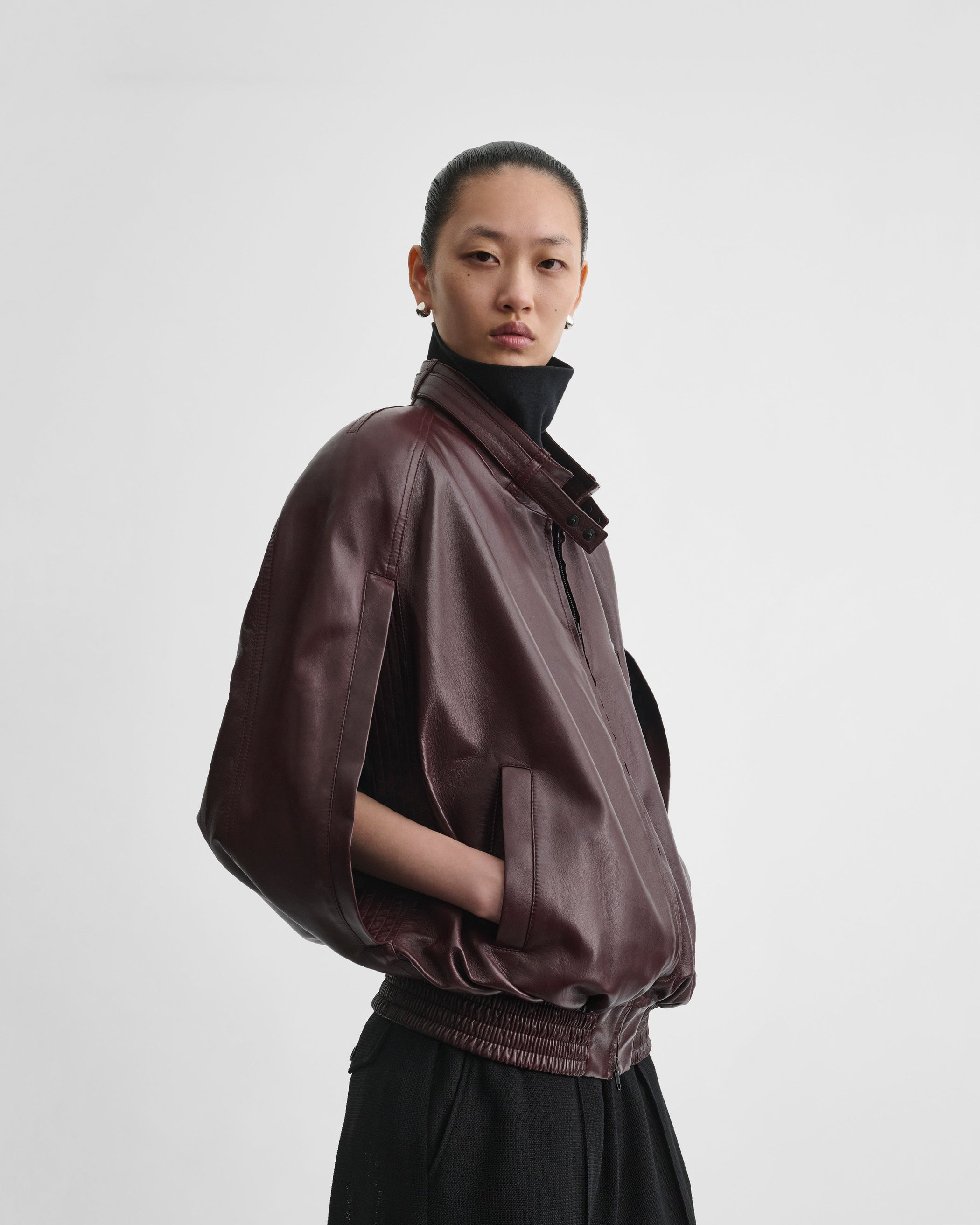 Side view of model wearing CAPE BOMBER in merlot leather