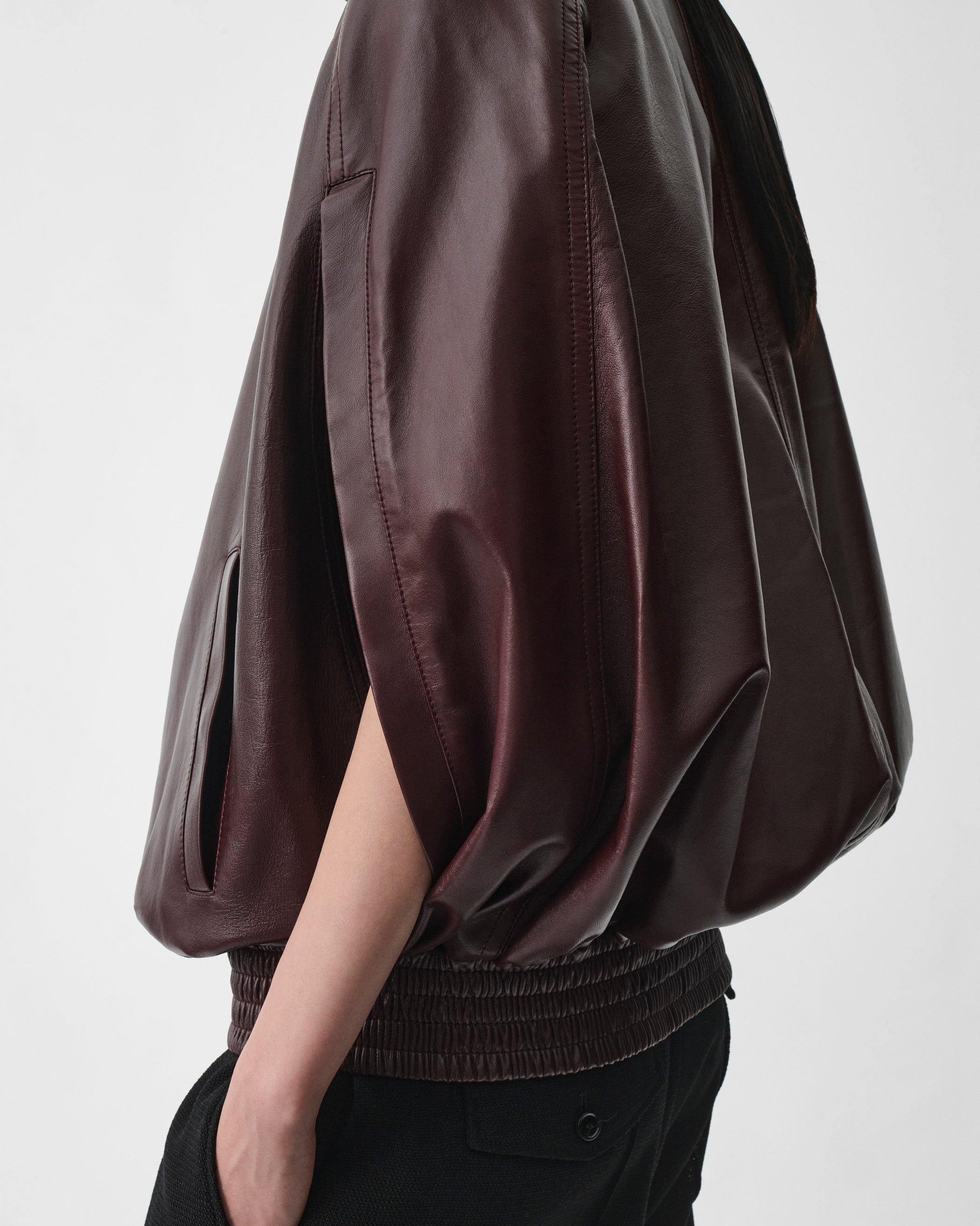 Detail side view of model wearing CAPE BOMBER in merlot leather