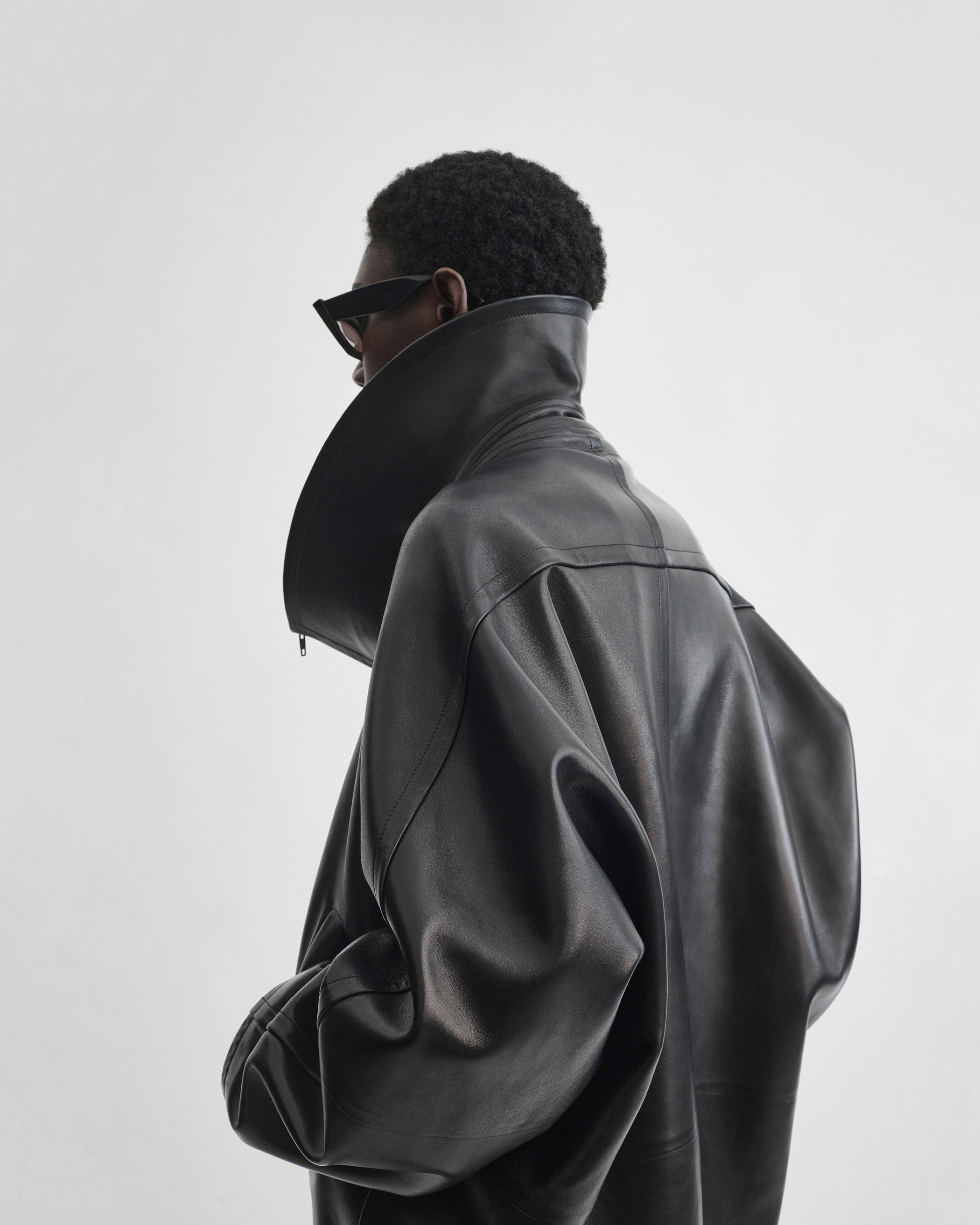 Angled back view of model wearing SWATHE JACKET in black leather