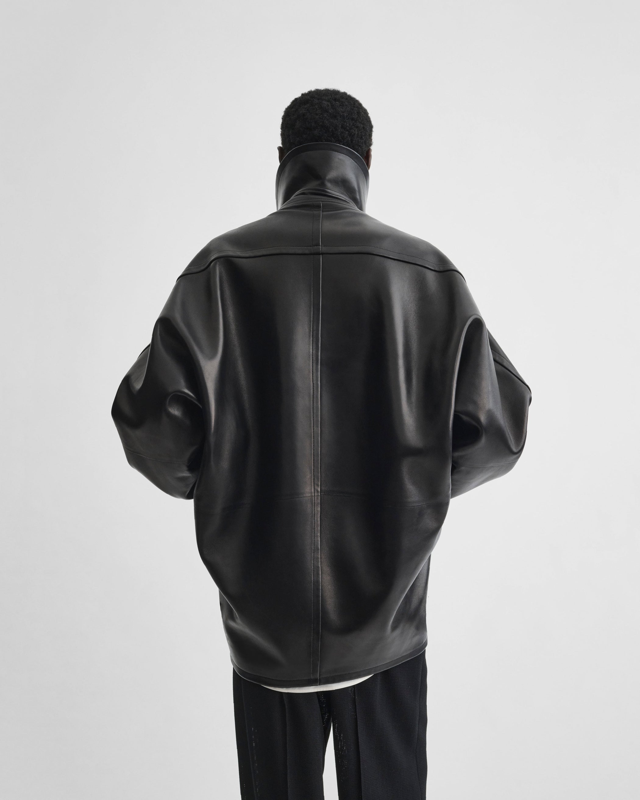 Back view of model wearing SWATHE JACKET in black leather