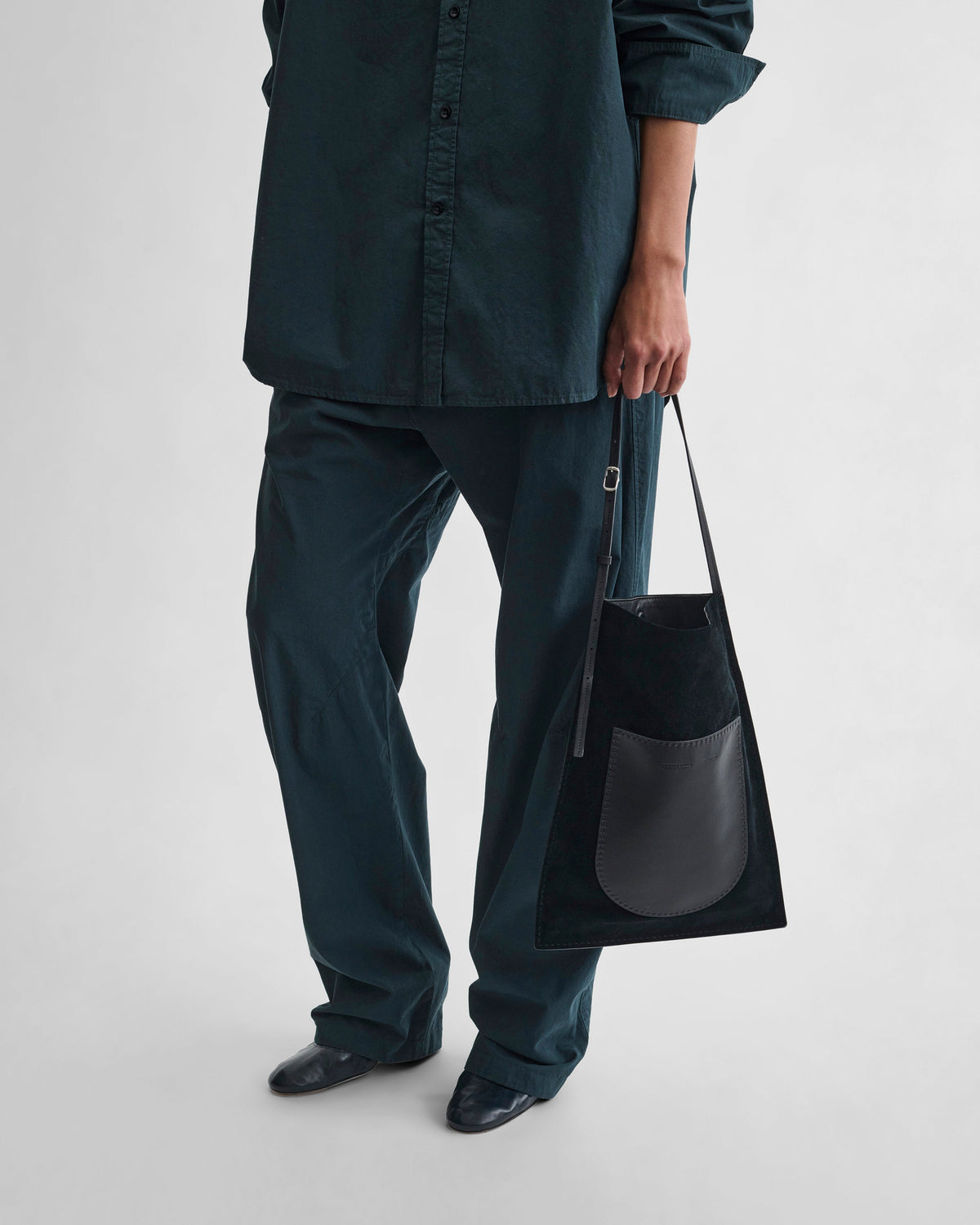 Front view of model holding GLOVE MESSENGER BAG in black suede