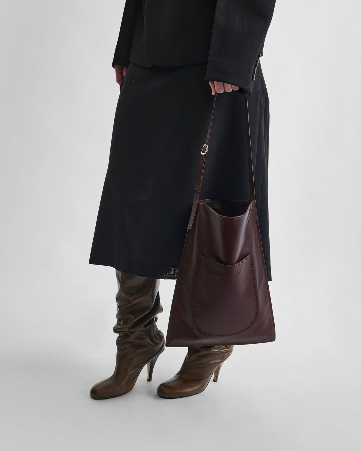Front view of model holding GLOVE MESSENGER BAG in oxblood leather