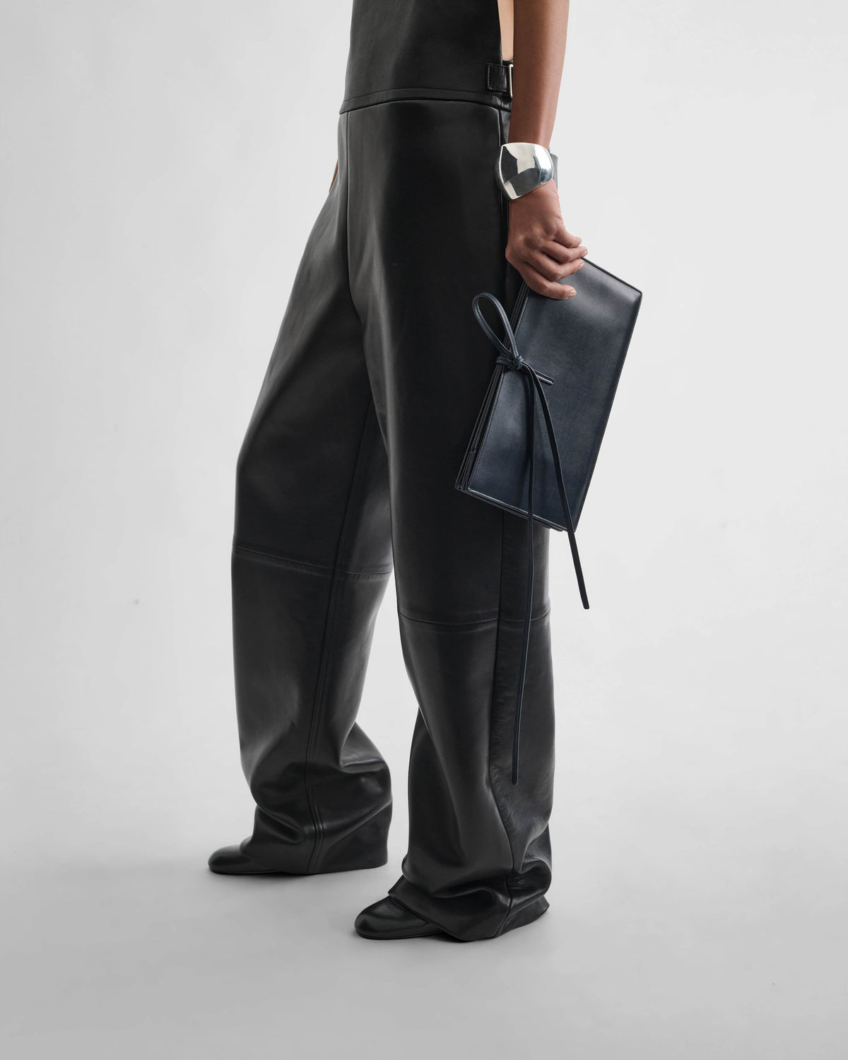 Side view of model wearing SPLAY CLUTCH in dark navy leather