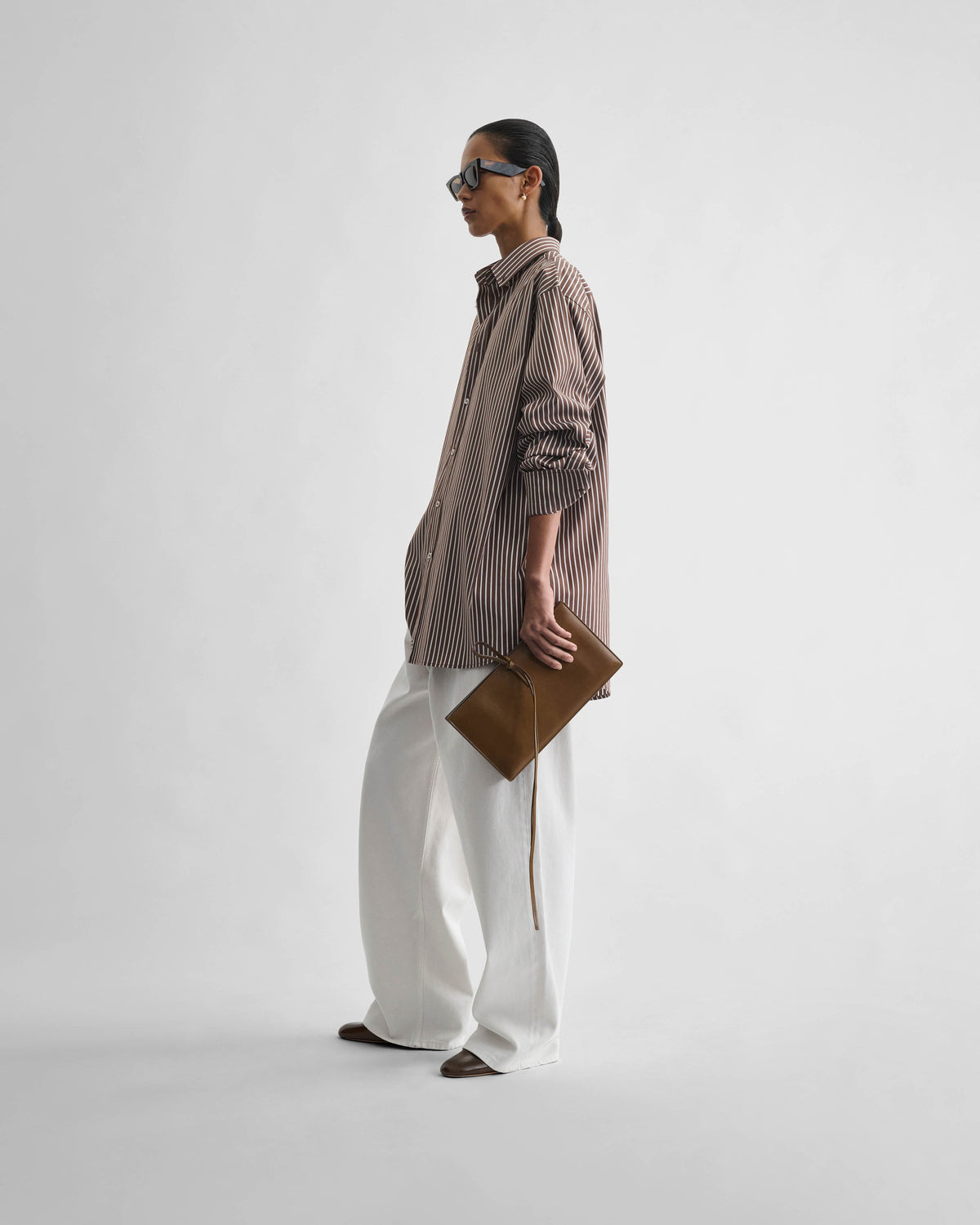Side view of model wearing SPLAY CLUTCH in bronze leather