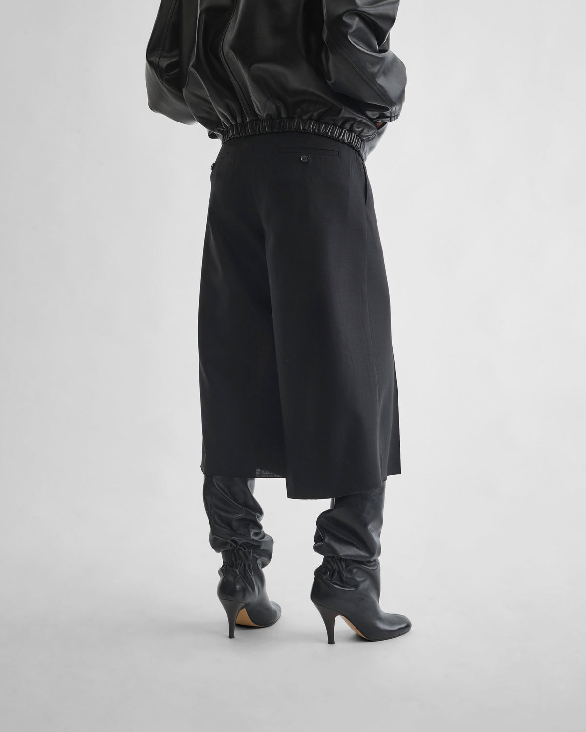 Back view of model wearing SPLIT SKIRT in black wool
