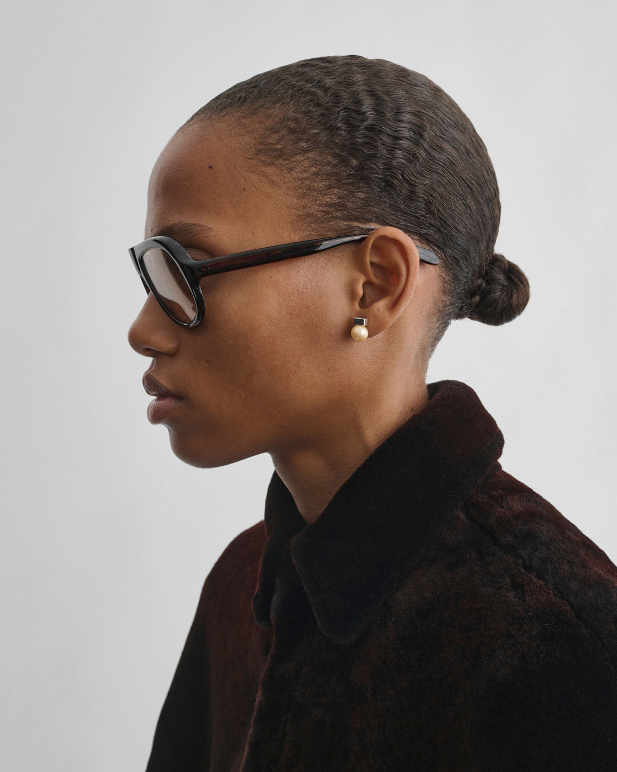 Side view of model wearing PEARL DROP STUDS in gold