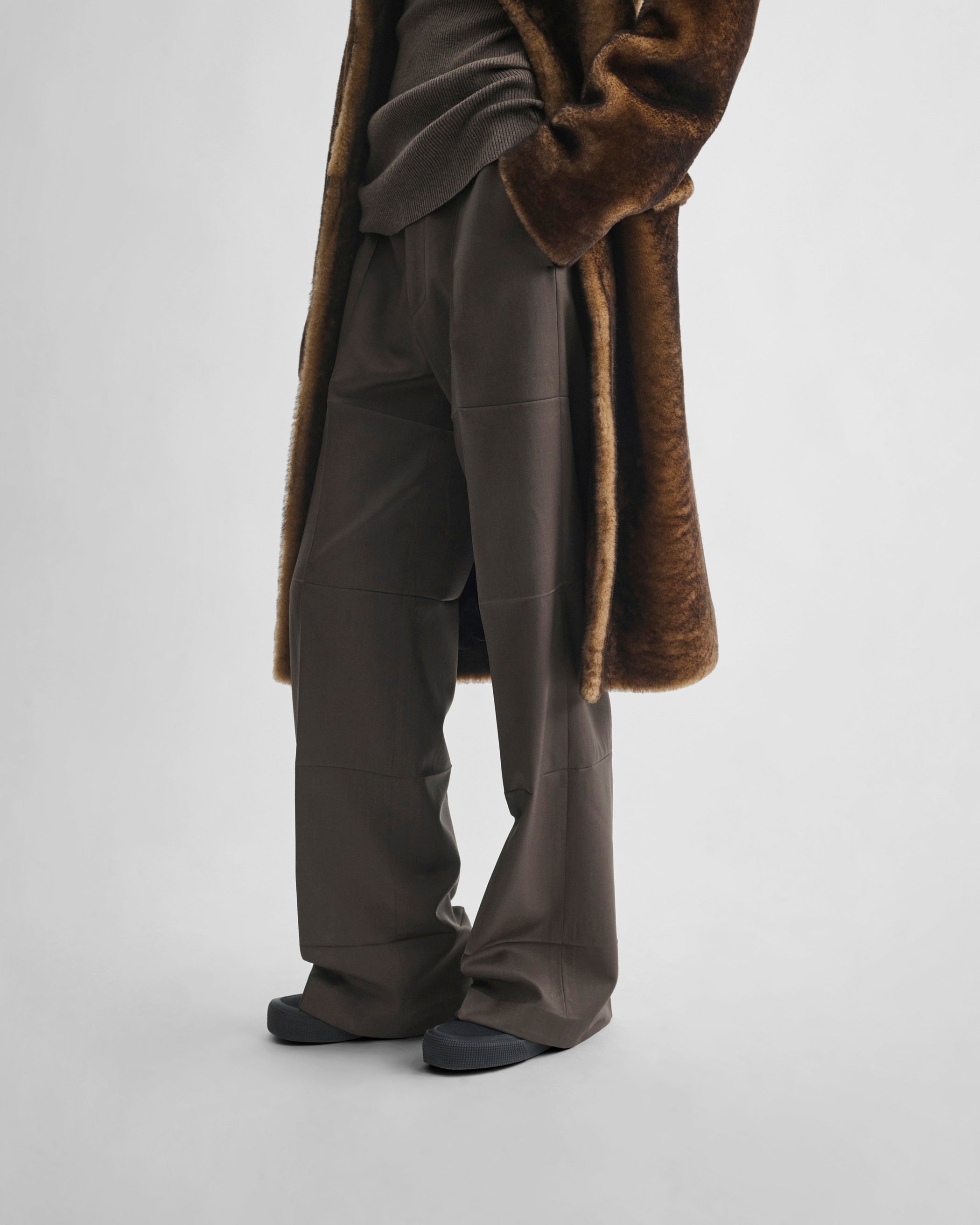 Side view of model wearing CREASED BOYISH TAILORED TROUSERS in brown khaki wool