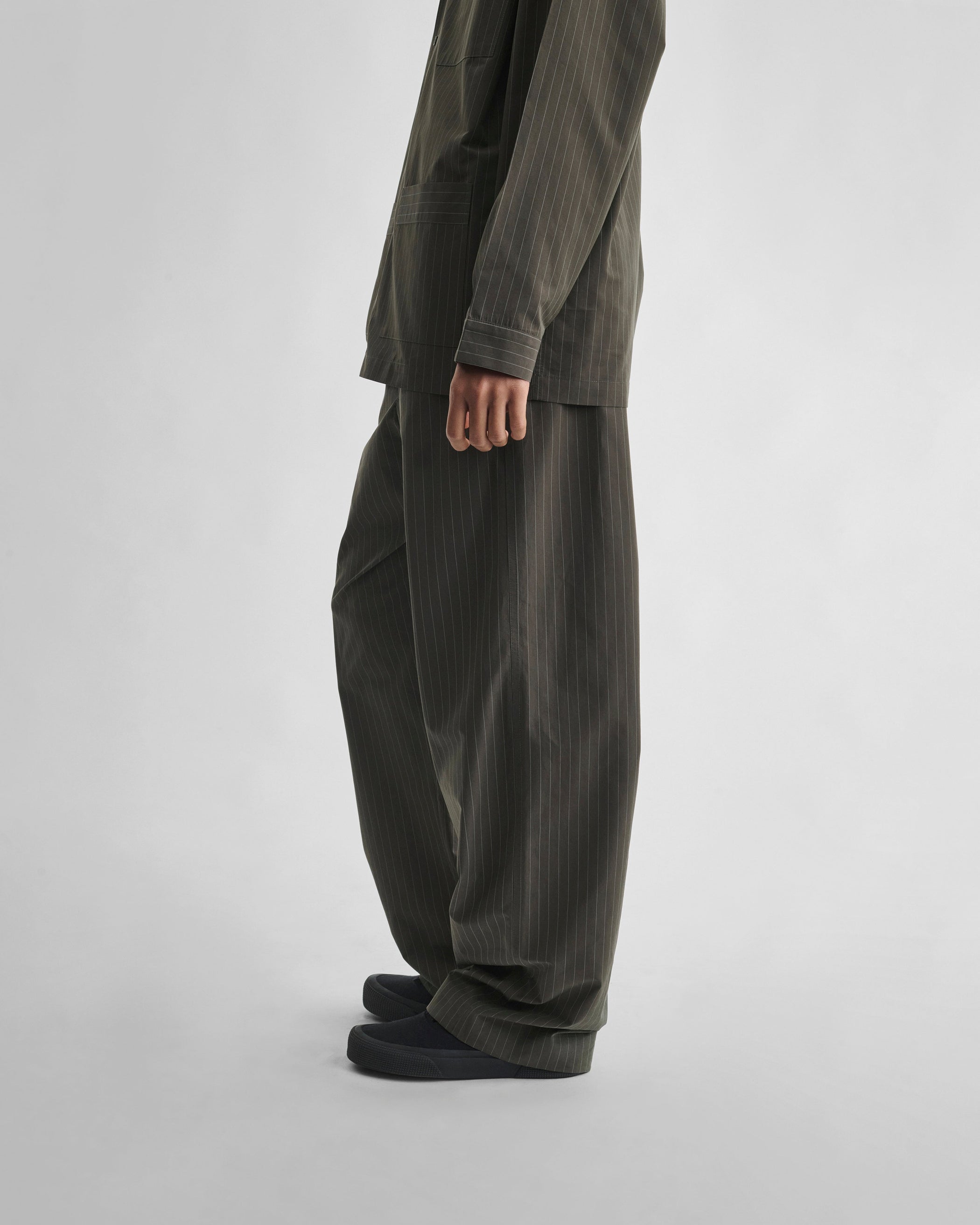Side view of model wearing PYJAMA TROUSERS in dark khaki cotton
