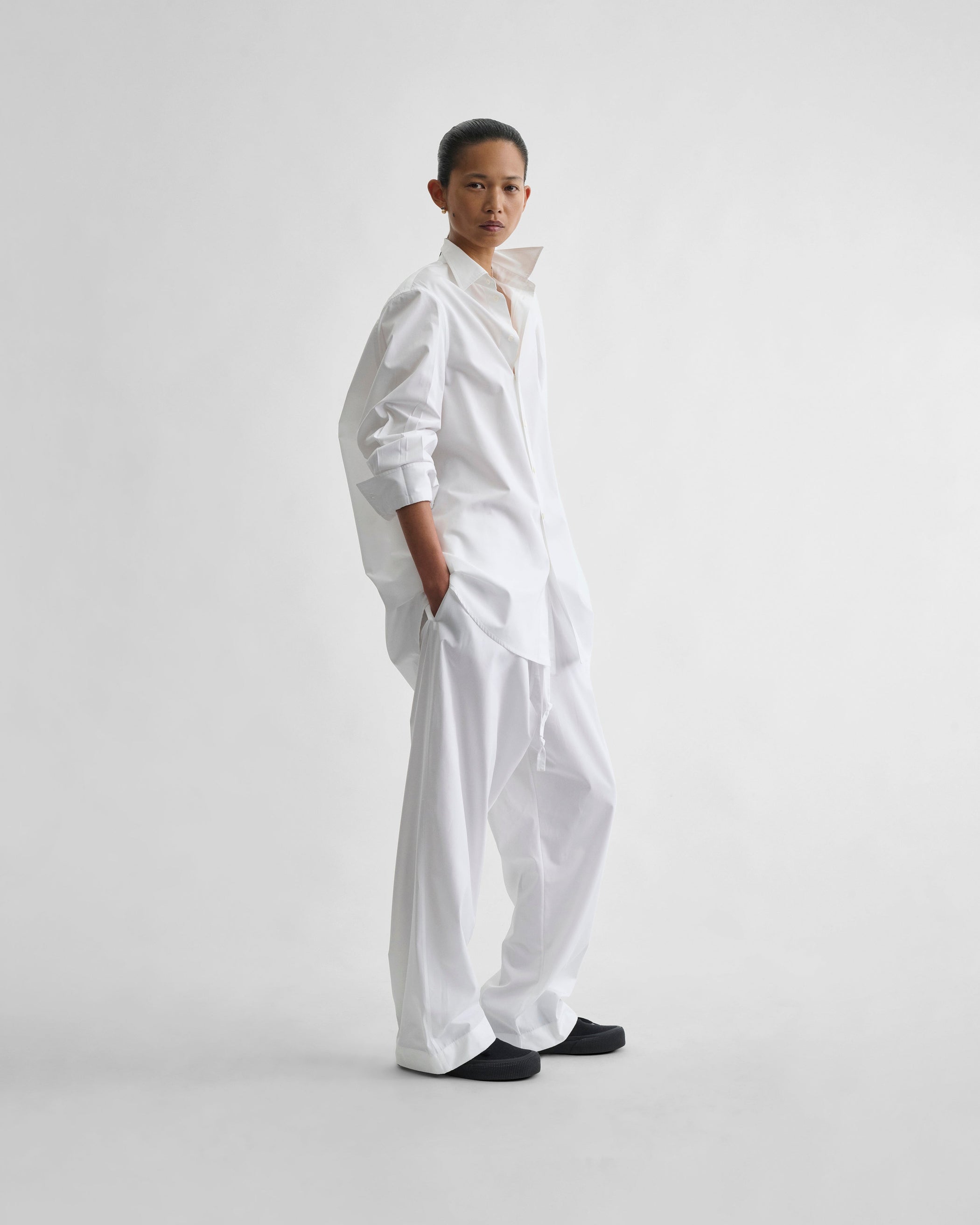 Angled front view of model wearing PYJAMA TROUSERS in white cotton