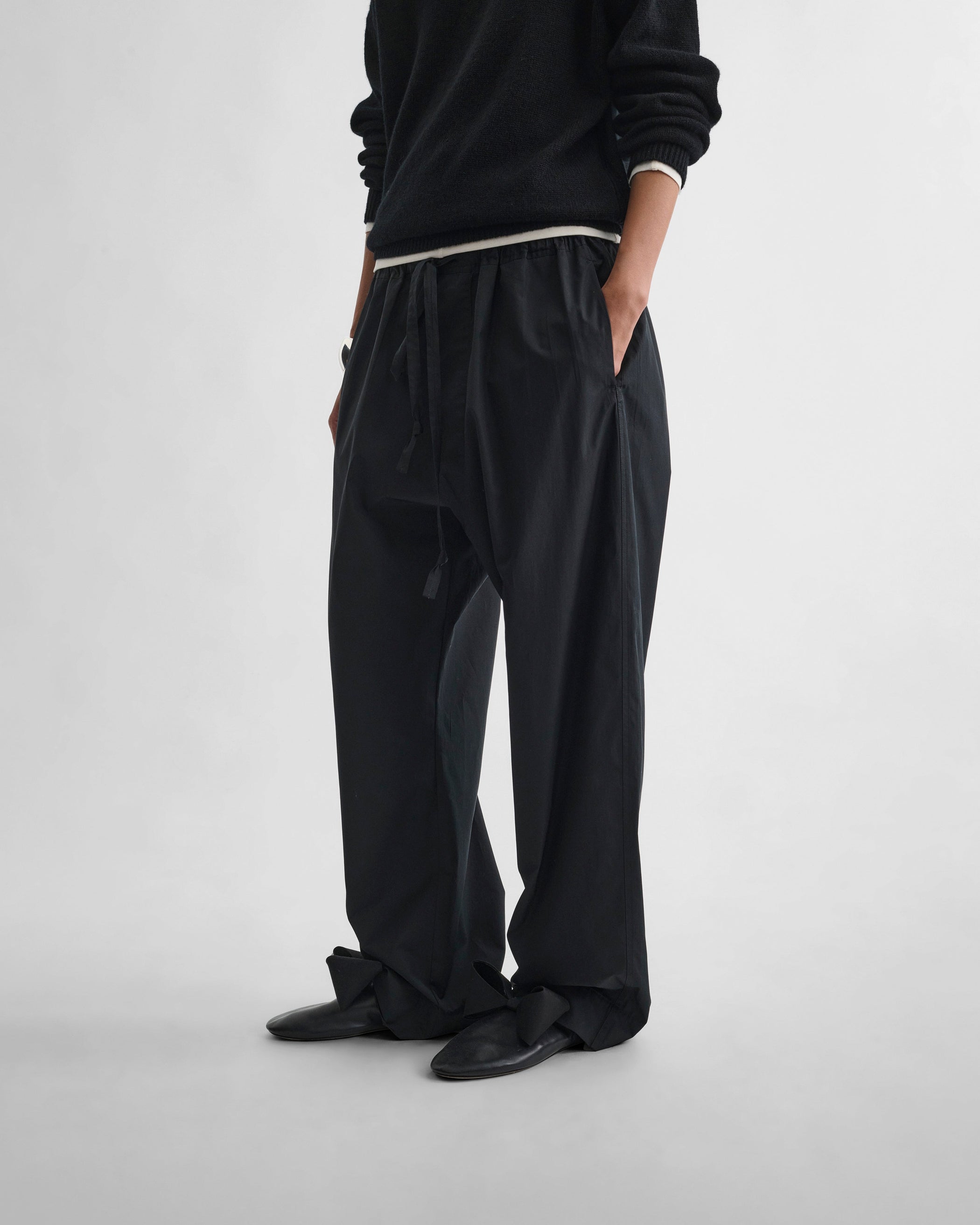 Angled front view of model wearing PYJAMA TROUSERS in black cotton